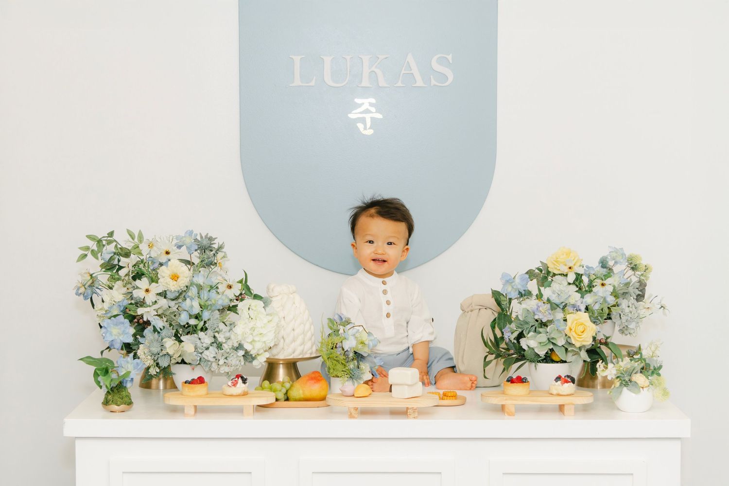 Minimalist birthday backdrop with soft blue circle and floral accents.