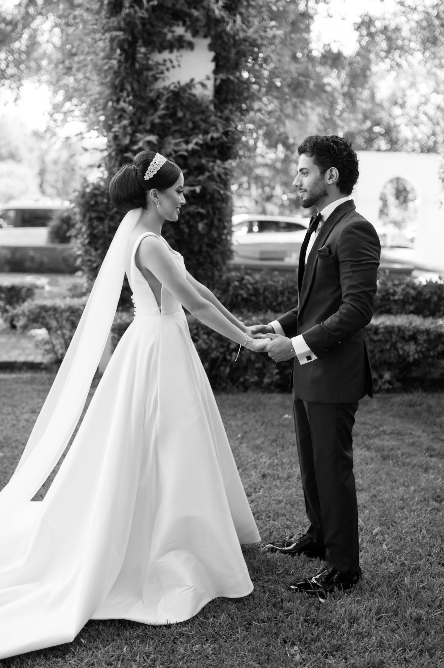 Bride and groom share first look moment in garden setting wearing classic wedding attire.
