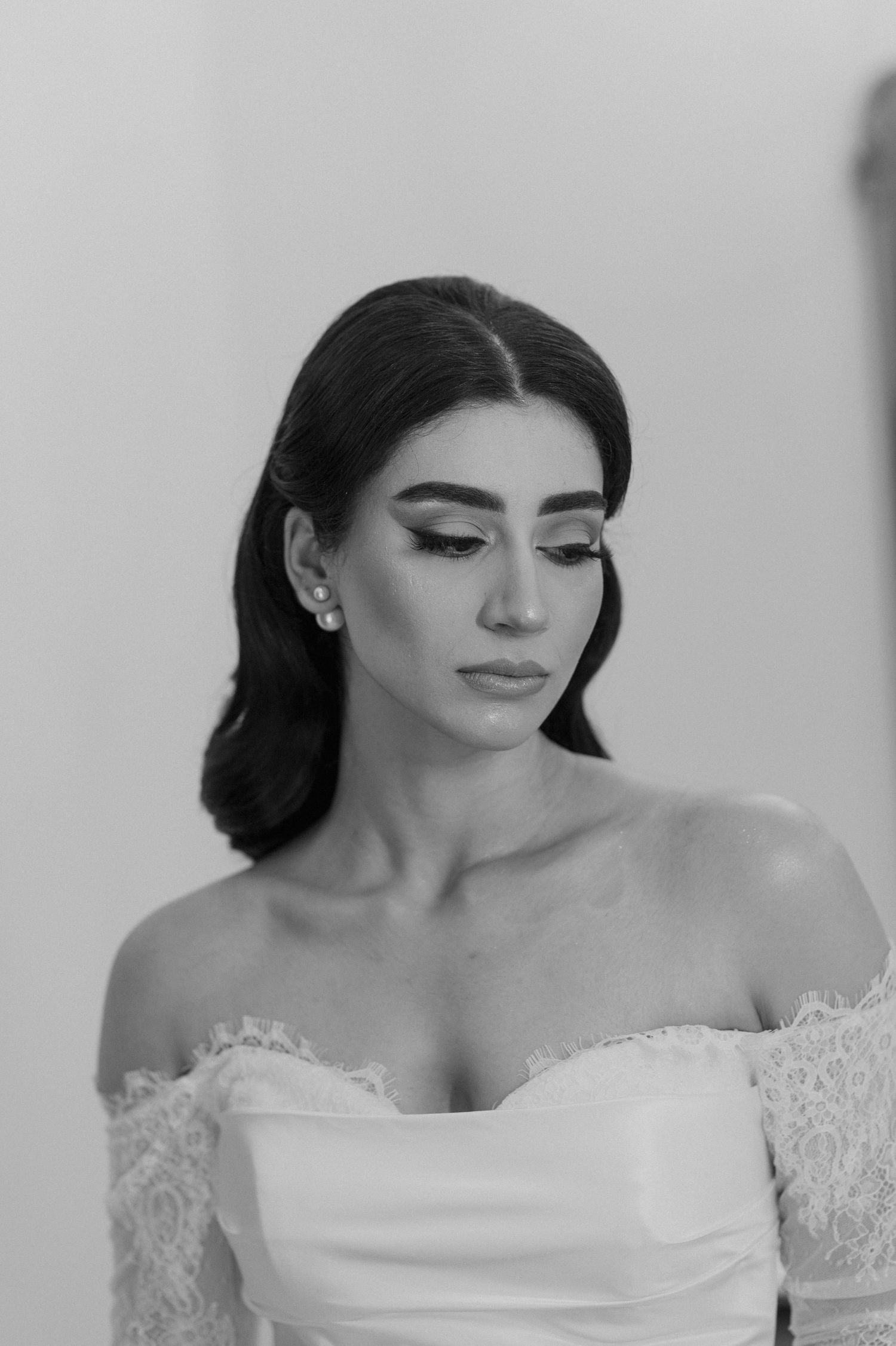 Dramatic black and white bridal portrait showcasing off-shoulder lace gown and elegant makeup.