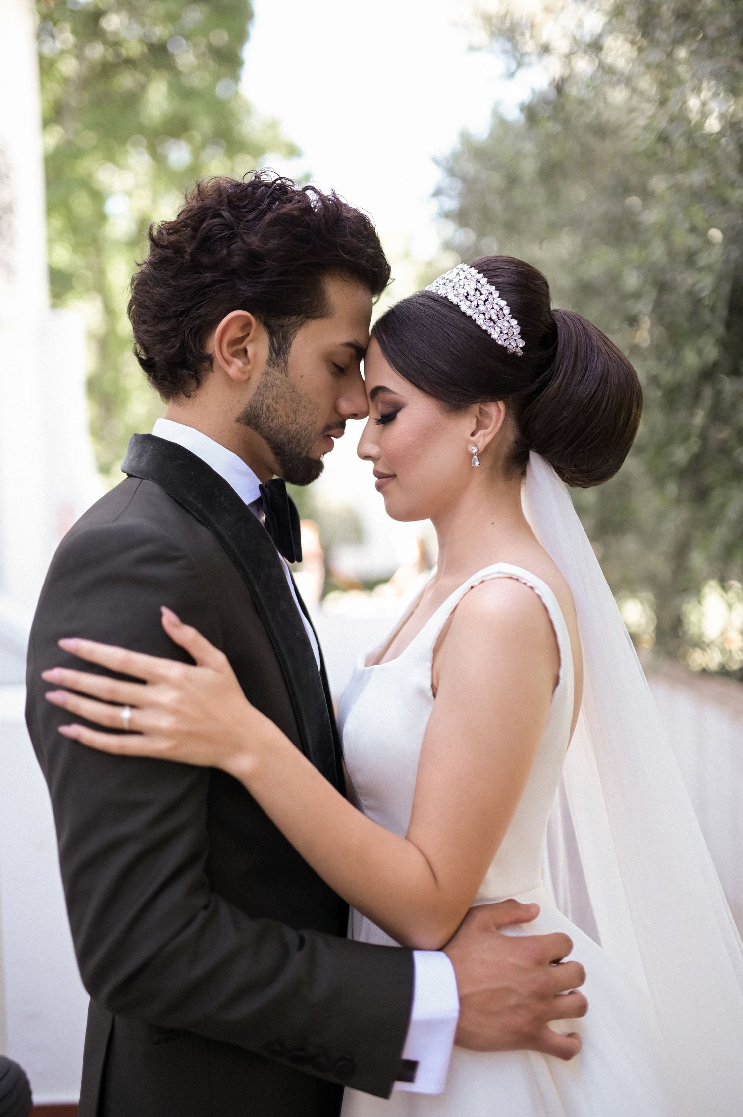 Newlyweds embrace in tender moment during outdoor wedding photoshoot.