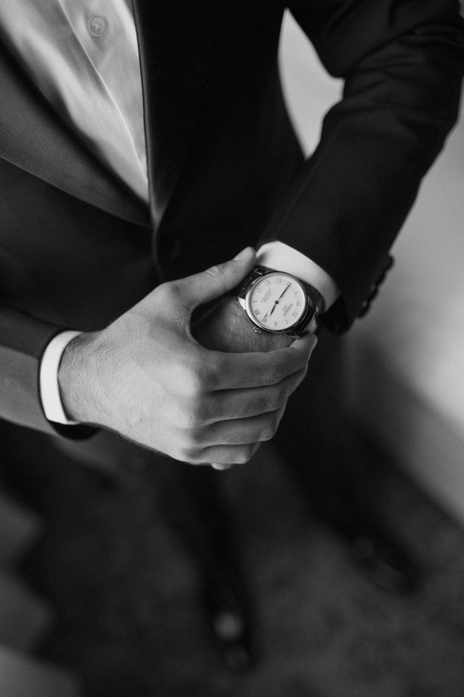Close up black and white photo of hands holding a wristwatch.