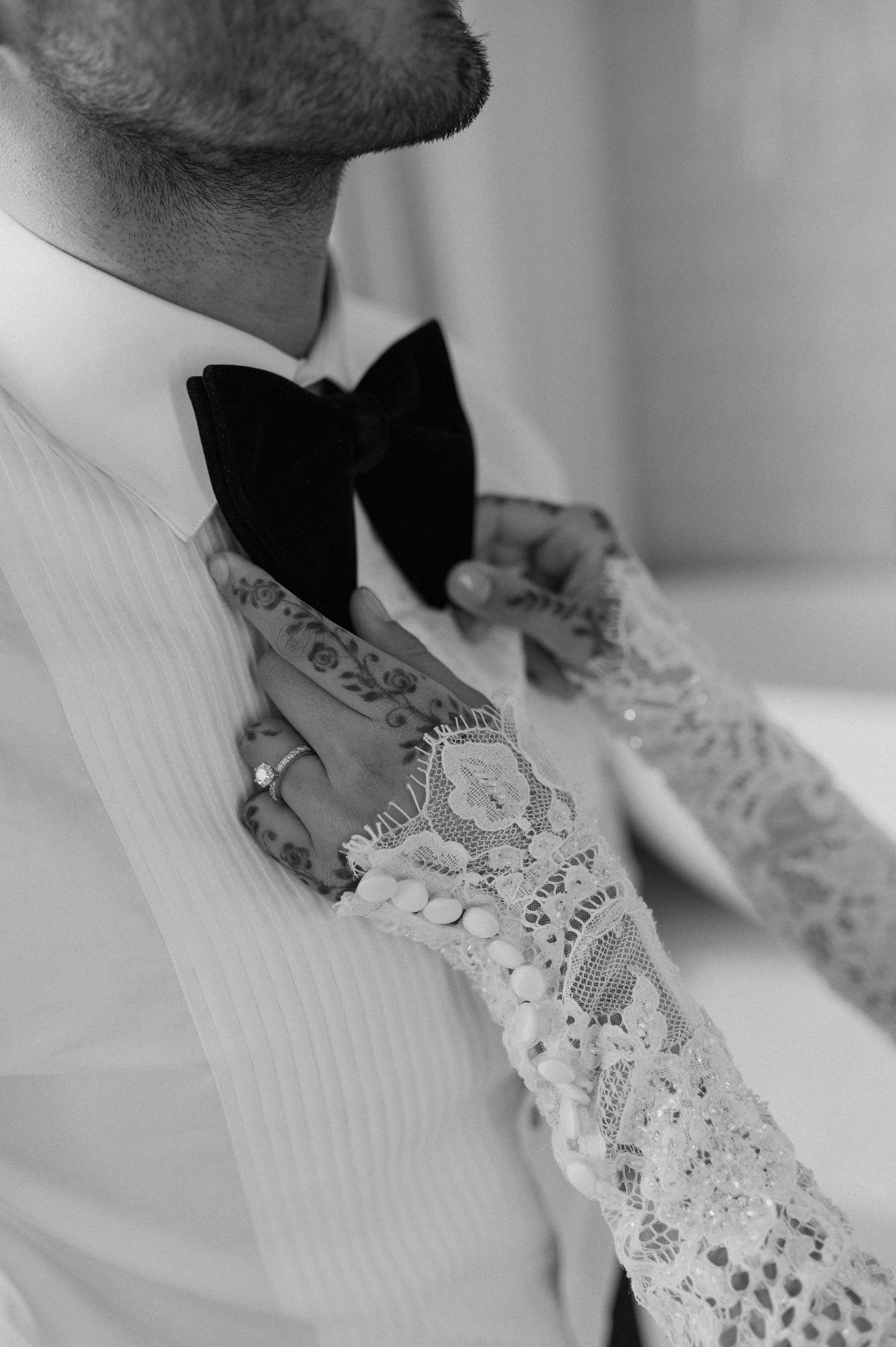 Detail shot of groom's bow tie and lace-detailed formal attire in black and white.