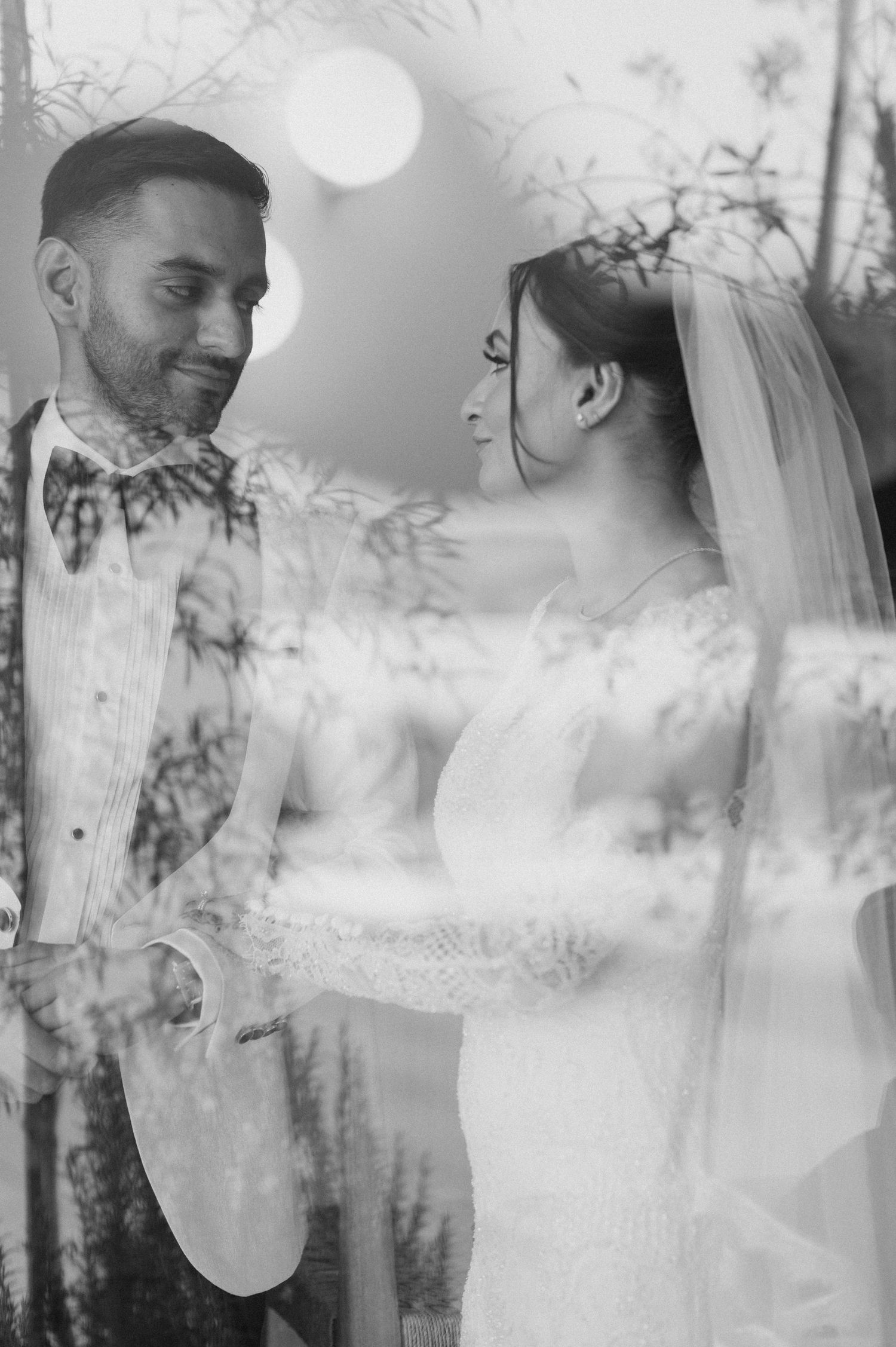 An artistic double exposure wedding portrait with romantic lighting and foliage overlay.