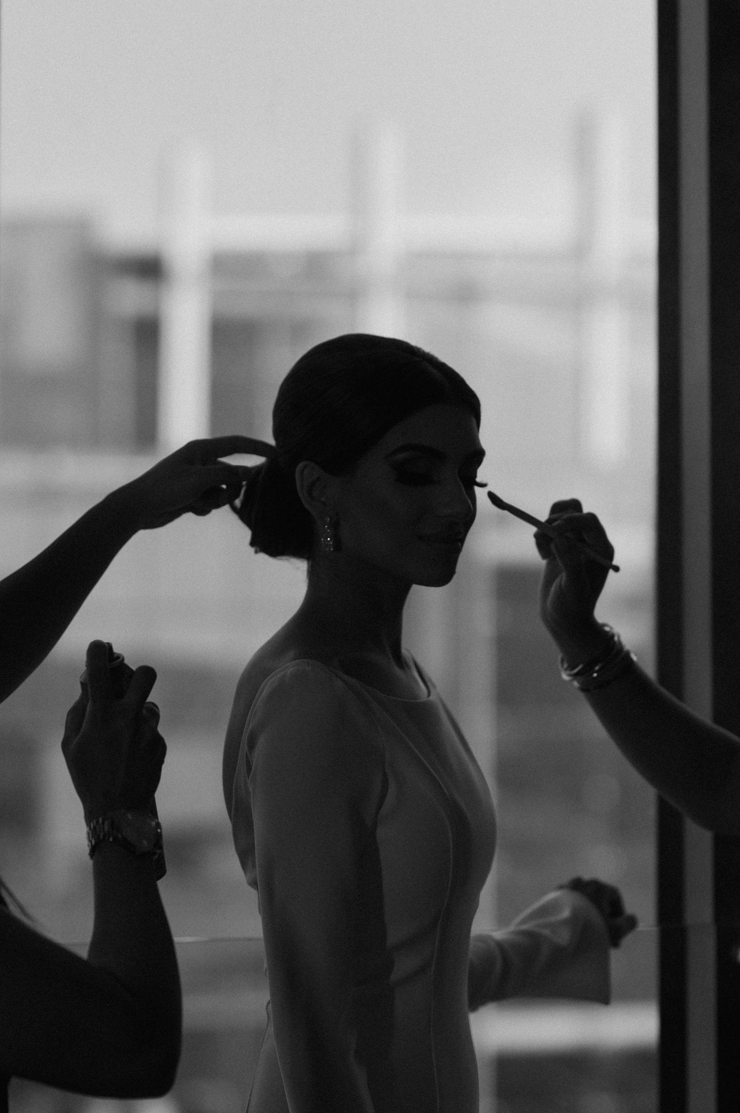 Silhouetted image of a bride getting her hair styled during wedding preparations.