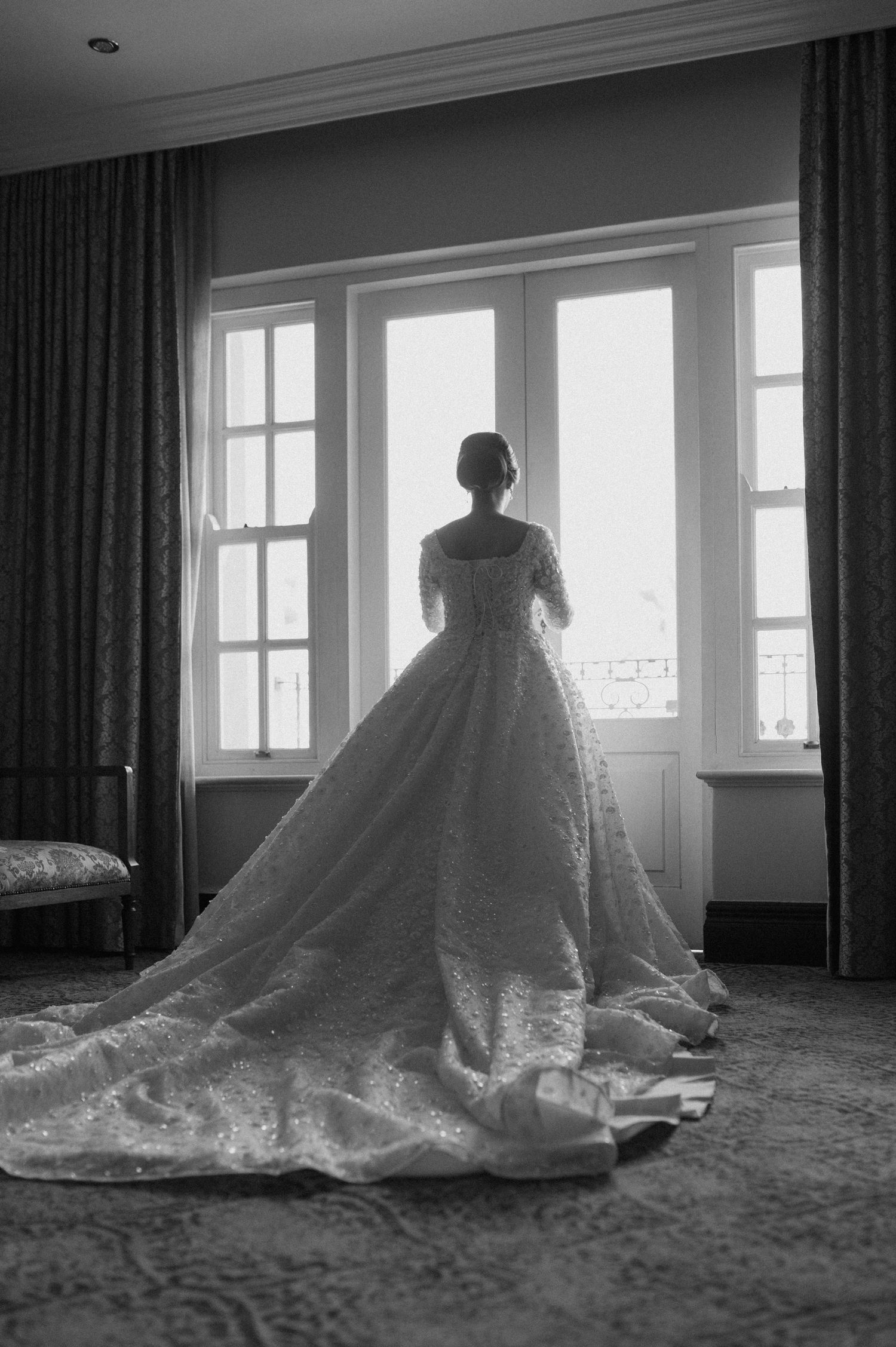 Silhouette of bride in ballgown wedding dress looking out window.