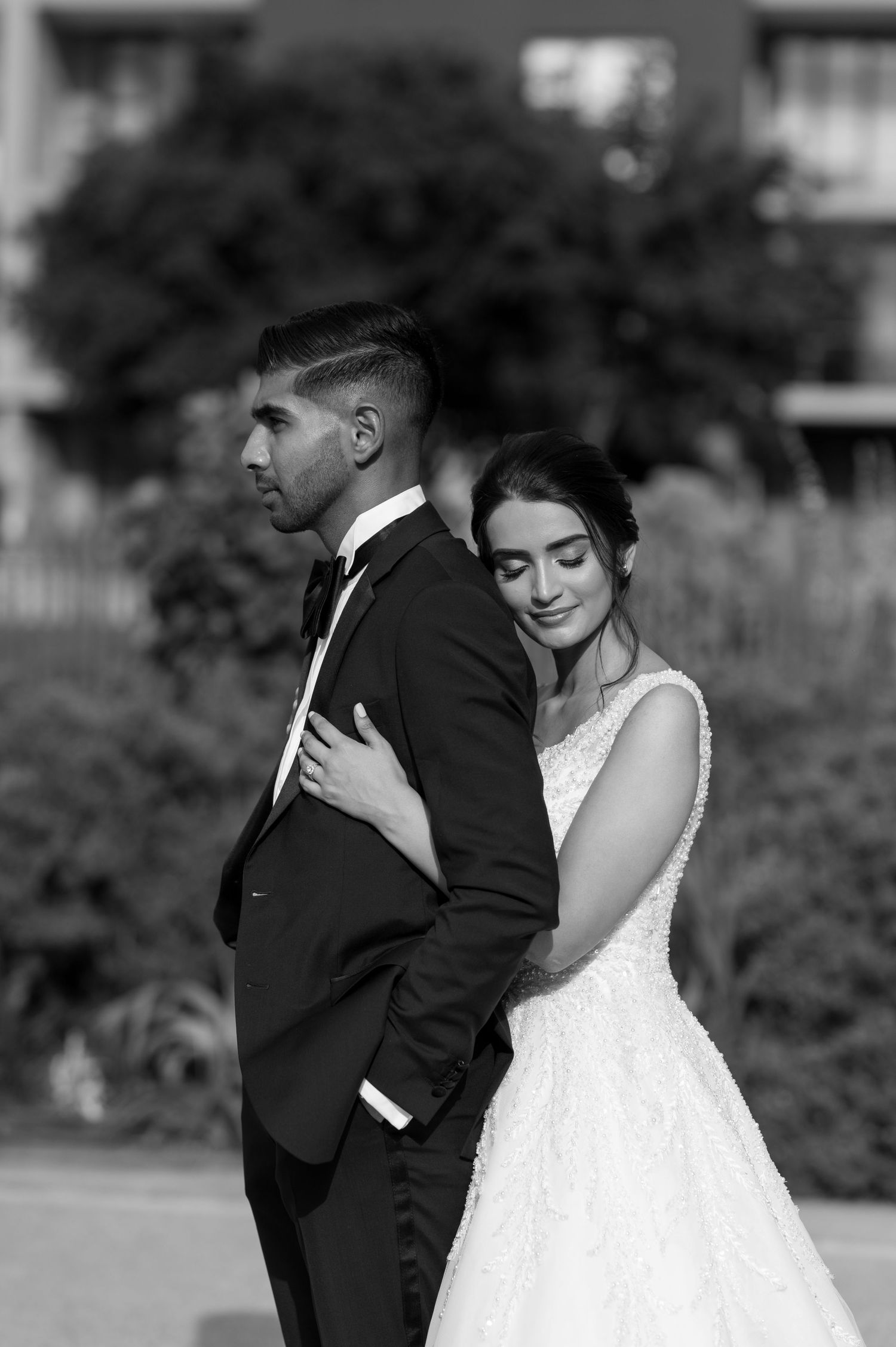 Black and white portrait of a wedding couple in an elegant pose outdoors.