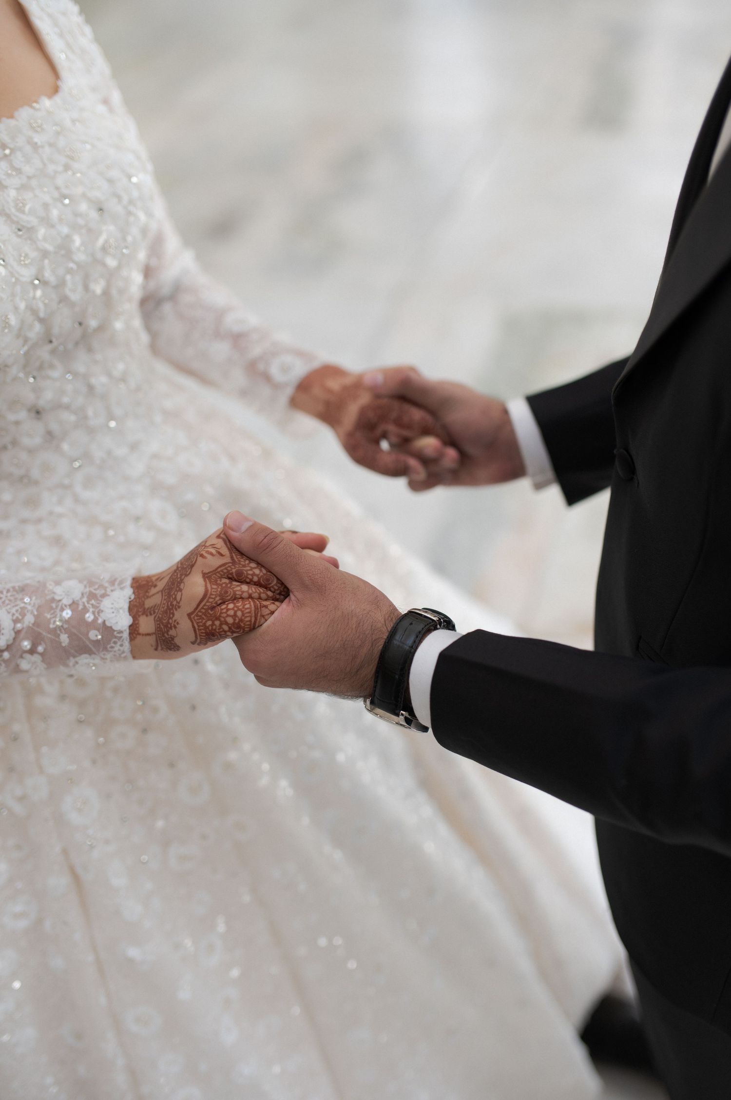 Close up of couple holding hands showing intricate henna designs.