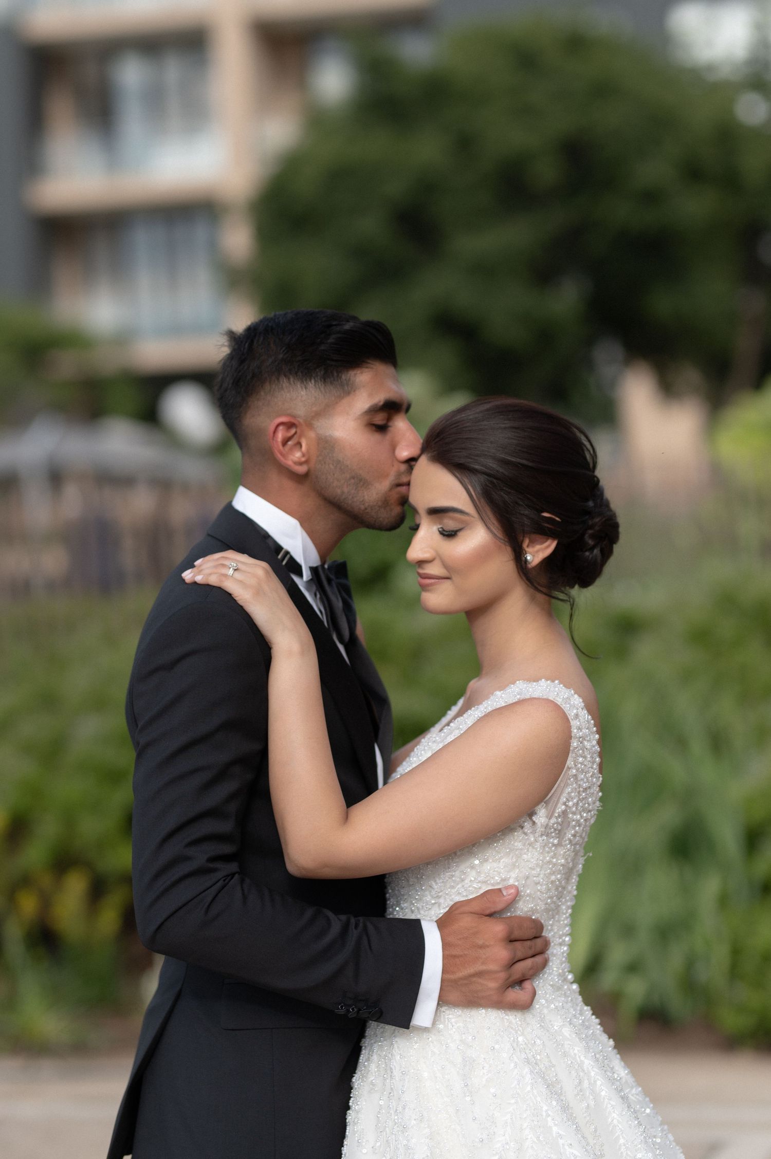 A romantic wedding portrait of a couple sharing an intimate moment outdoors.
