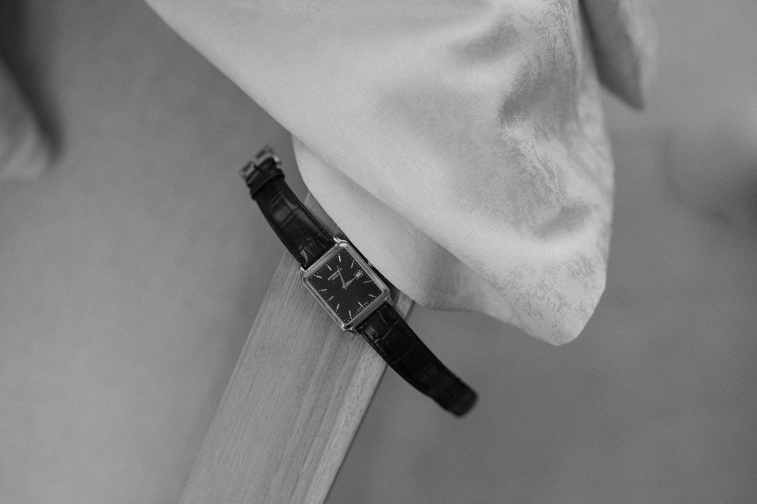Close-up detail of an elegant wristwatch against white fabric.