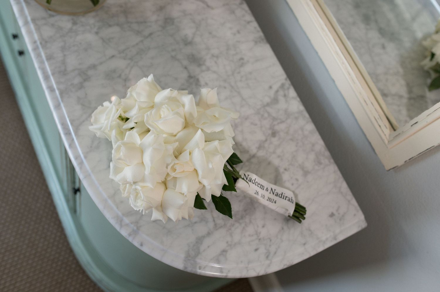 An elegant white bridal bouquet rests on a marble surface.
