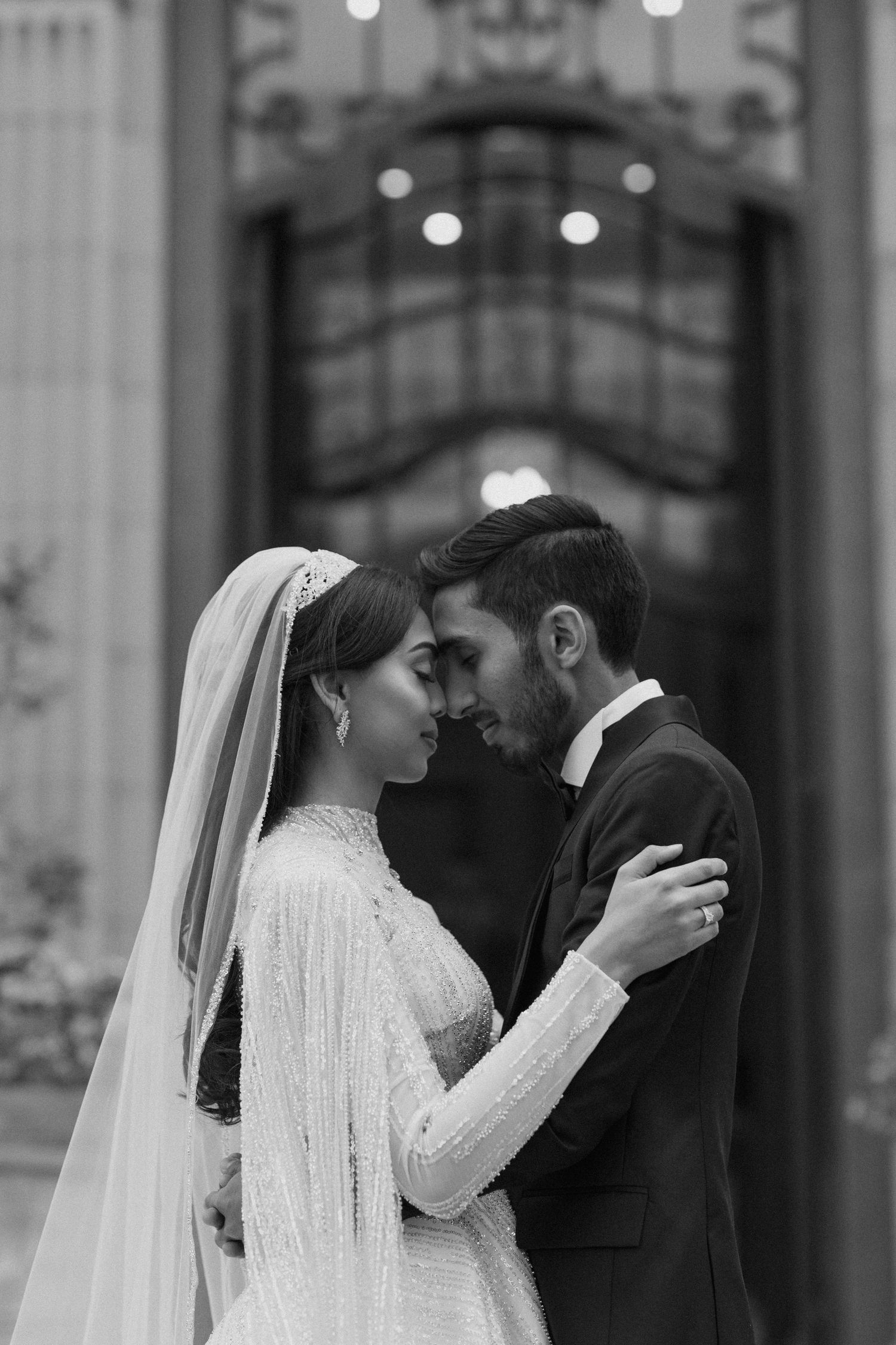 A romantic black and white portrait of newlyweds sharing an intimate moment.