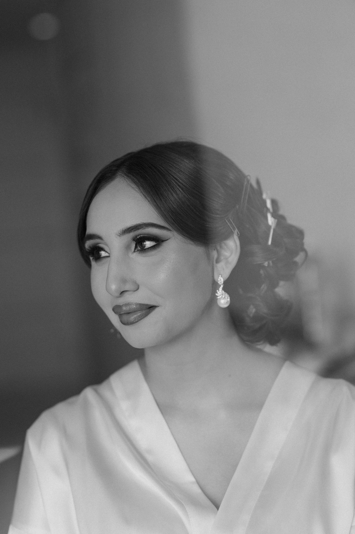 Elegant bridal portrait in black and white showing glamorous makeup and pearl drop earrings.