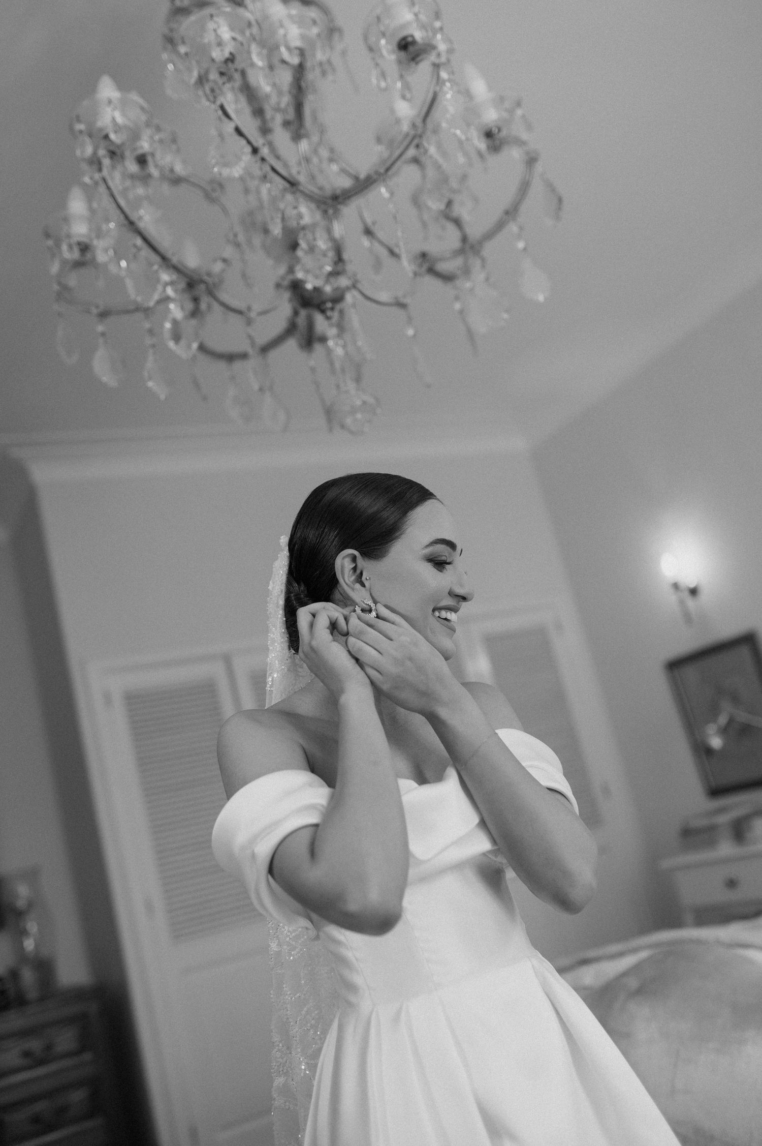 A classic black and white portrait under an ornate crystal chandelier.