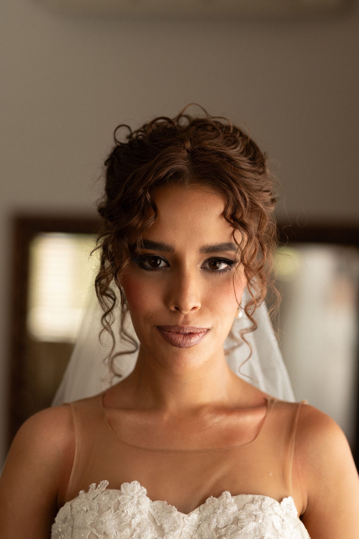 Portrait of bride with curly updo hairstyle and white wedding dress.