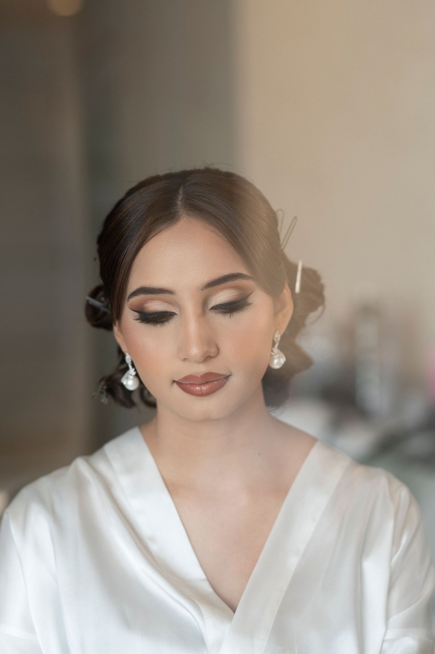 Close up of bridal makeup and hairstyle with pearl earrings.