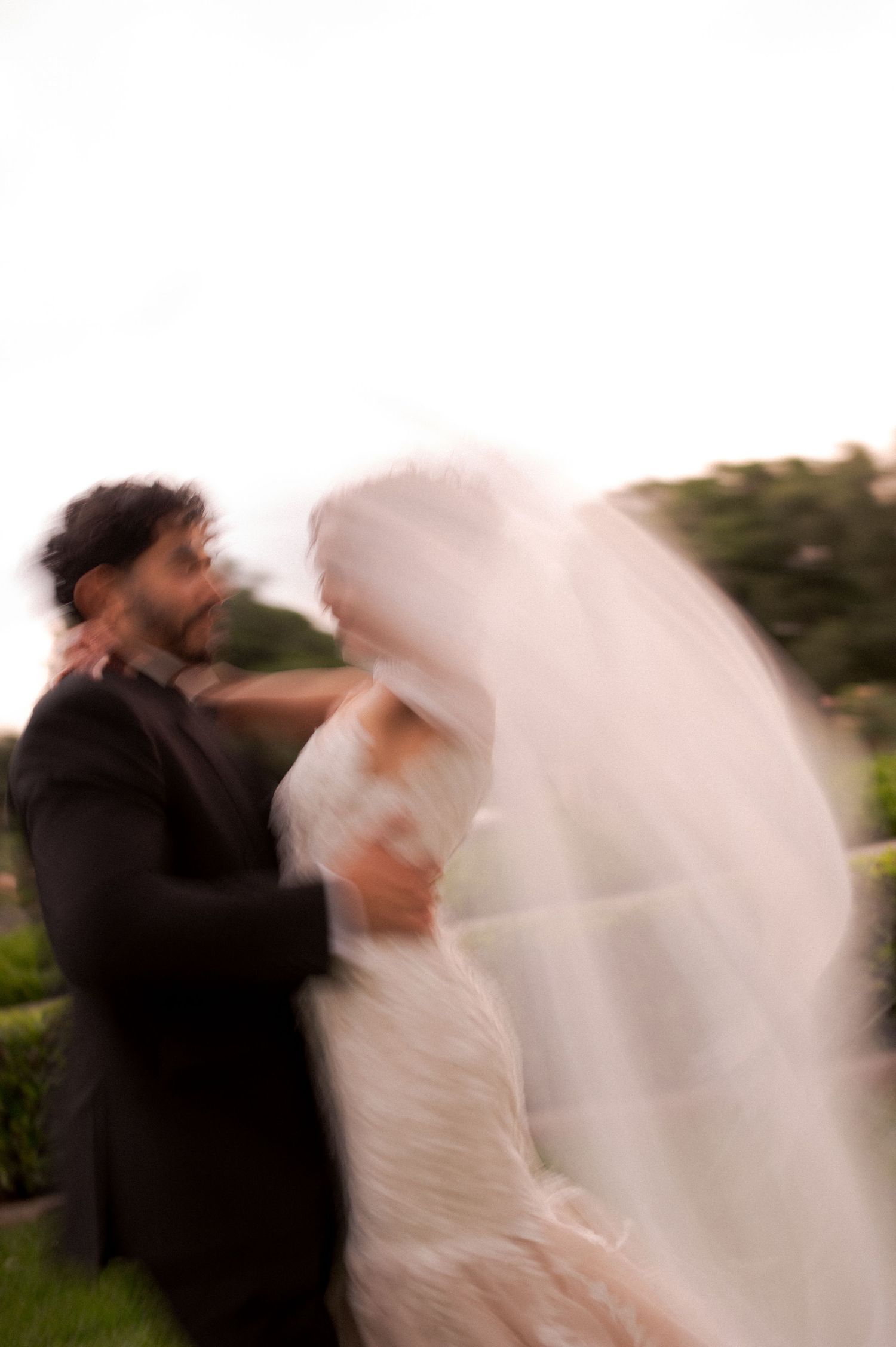 Motion blur capture of couple dancing together outdoors in wedding attire.