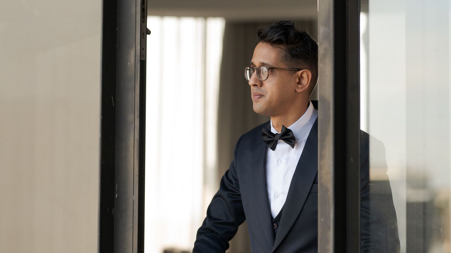 A groom in a classic black tuxedo and bow tie looking dapper on his wedding day.