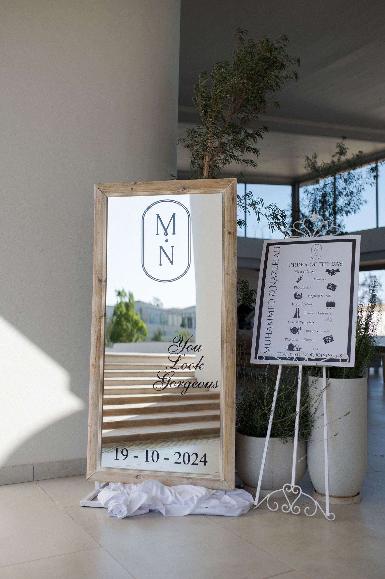 Wedding welcome mirror sign with monogram and date 19-10-2024 displayed on wooden frame.
