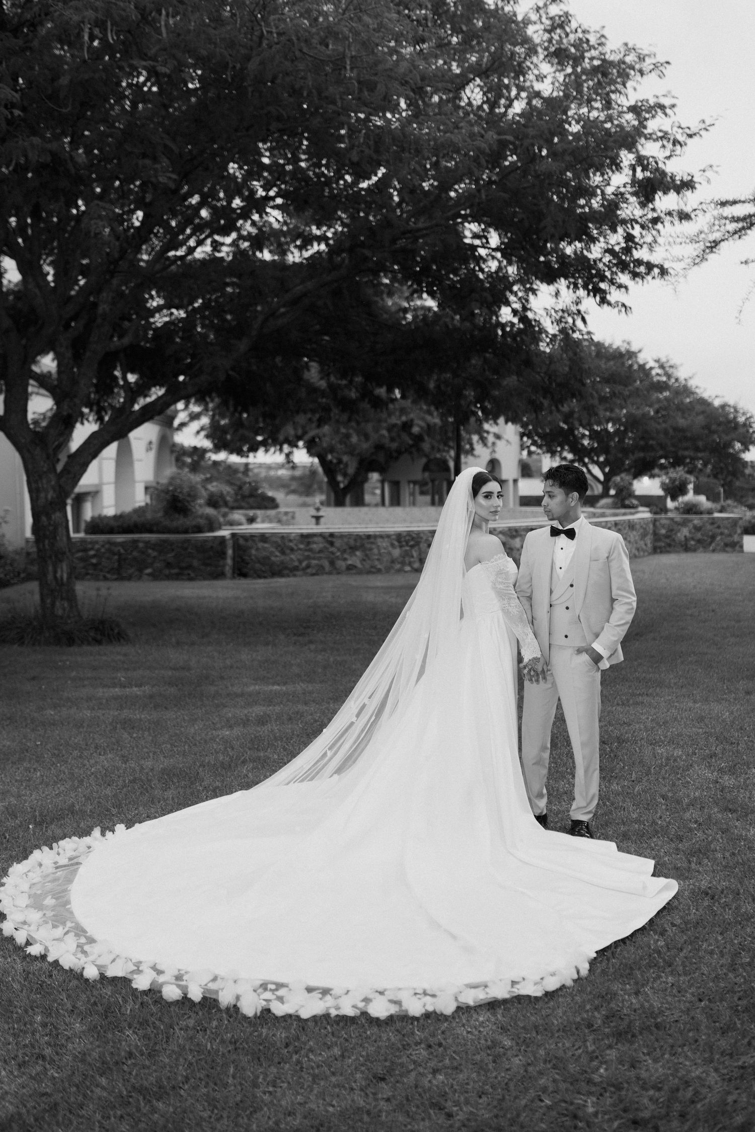 Black and white portrait of newlyweds showcasing dramatic cathedral veil with lace trim.