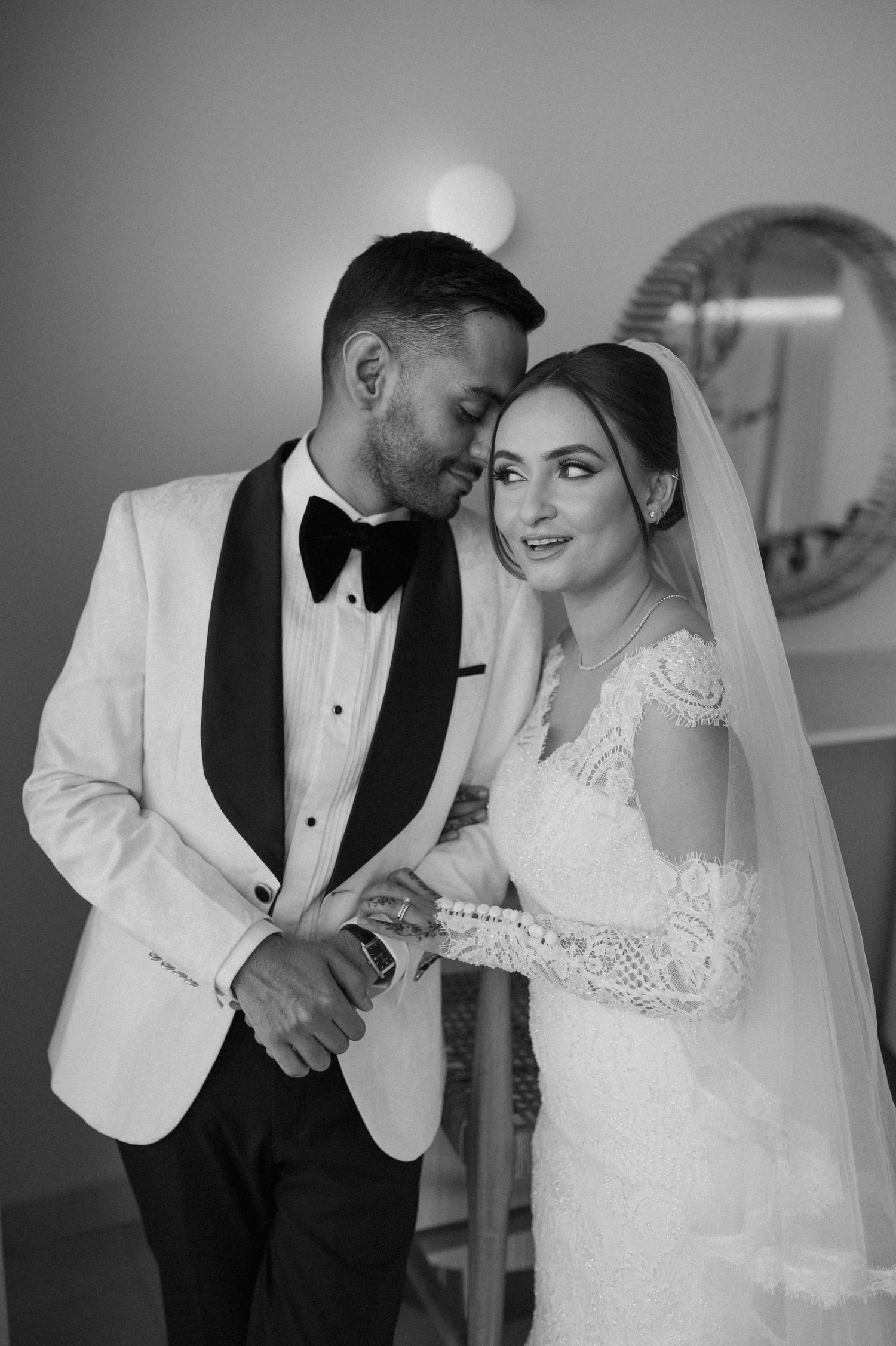 Black and white portrait of newlyweds sharing an intimate moment in formal wedding attire.