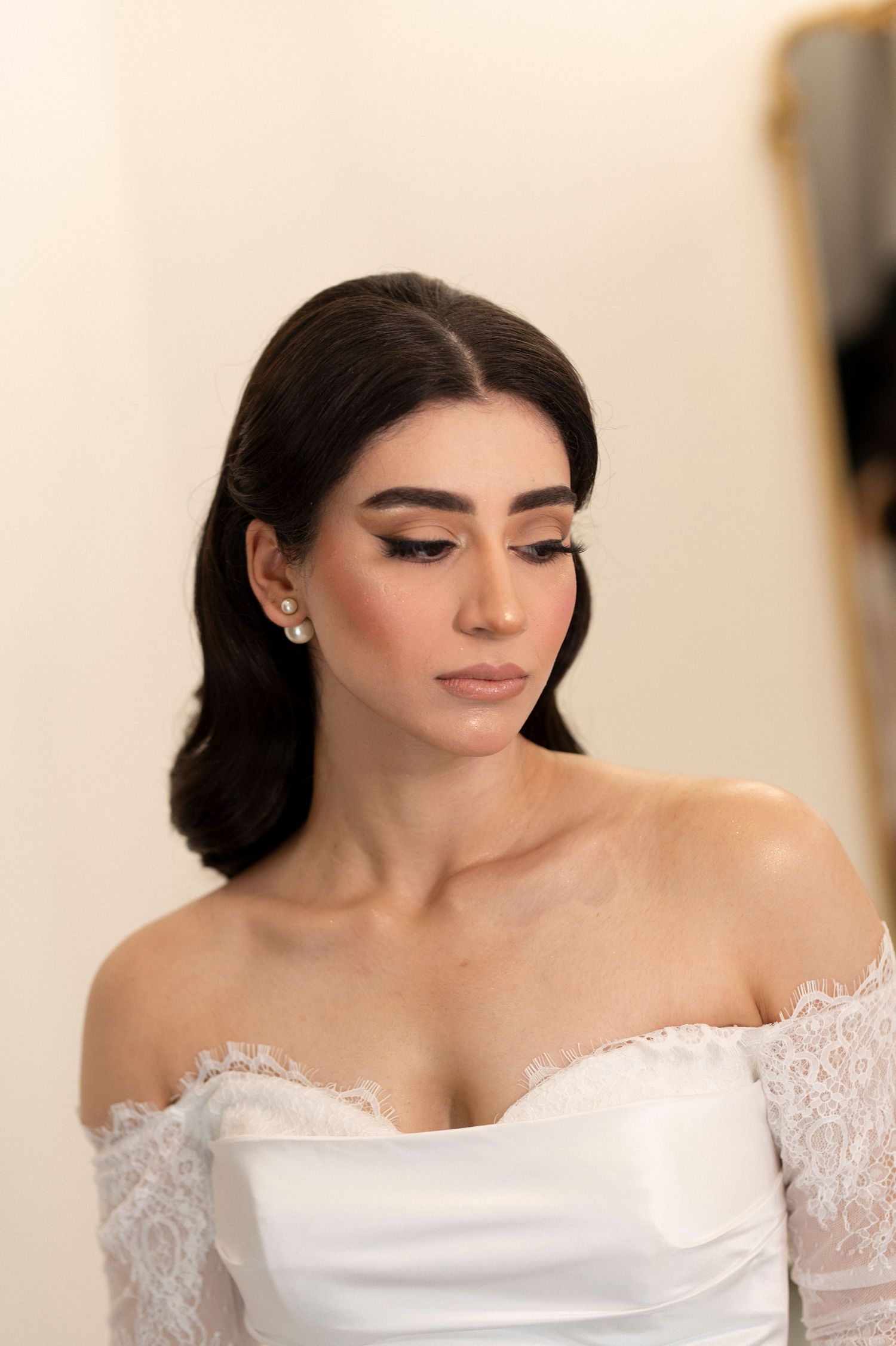Close up bridal portrait showing delicate lace detail and dramatic makeup with dark wavy hair.