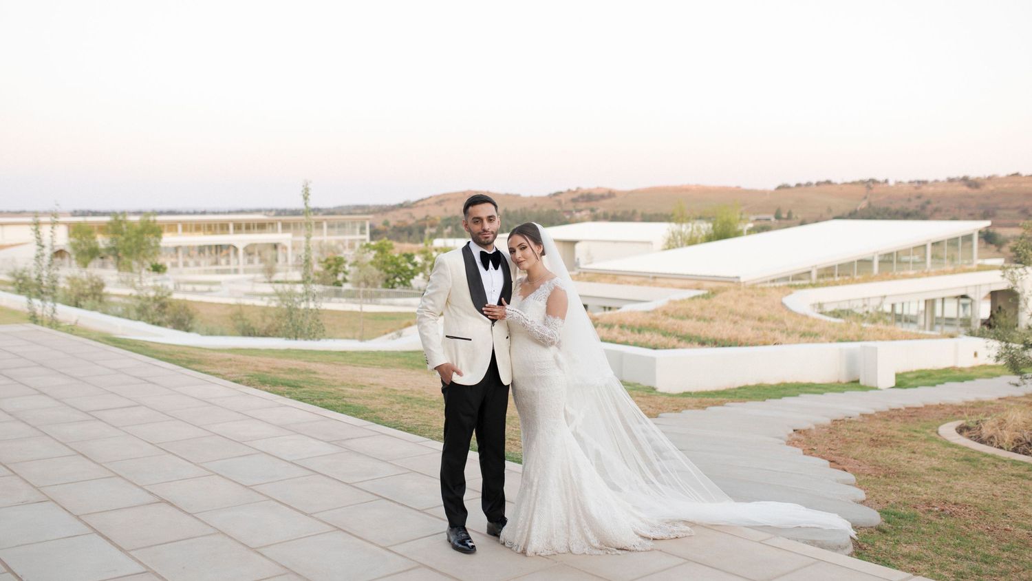 A romantic wedding portrait on a hilltop with scenic views at golden hour.