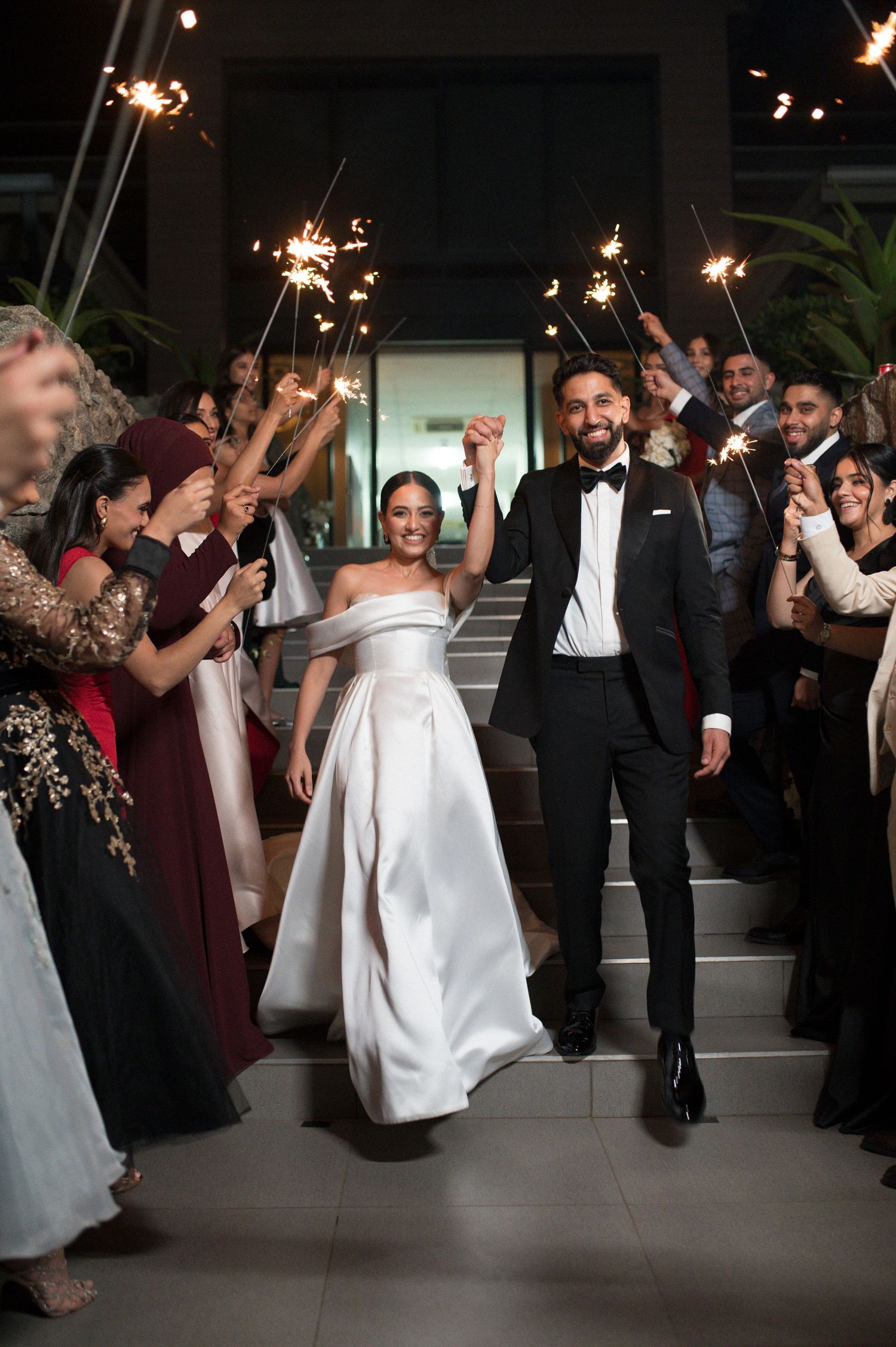 Wedding celebration with sparkler exit and guests lining the stairs.