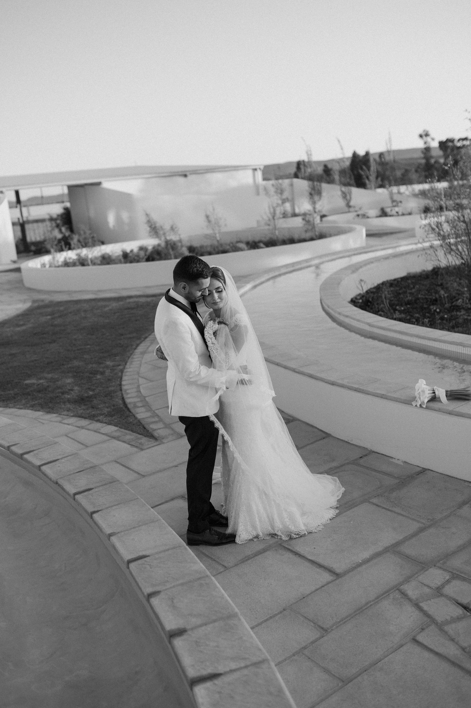 Black and white romantic wedding moment on curved garden path.