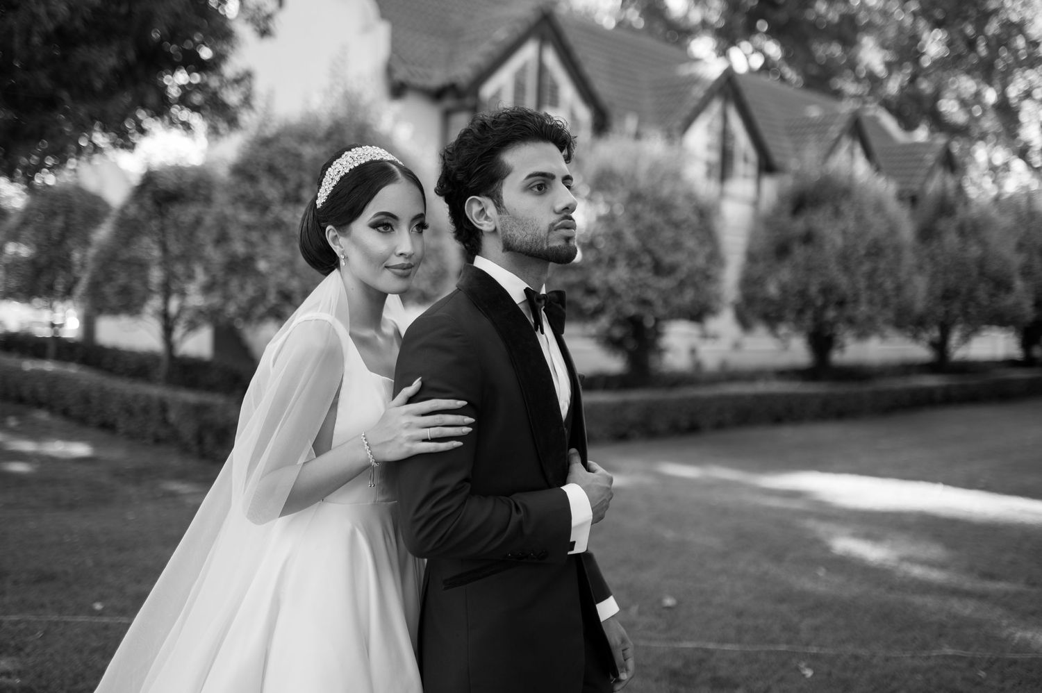 Romantic black and white wedding portrait in front of Tudor-style homes.