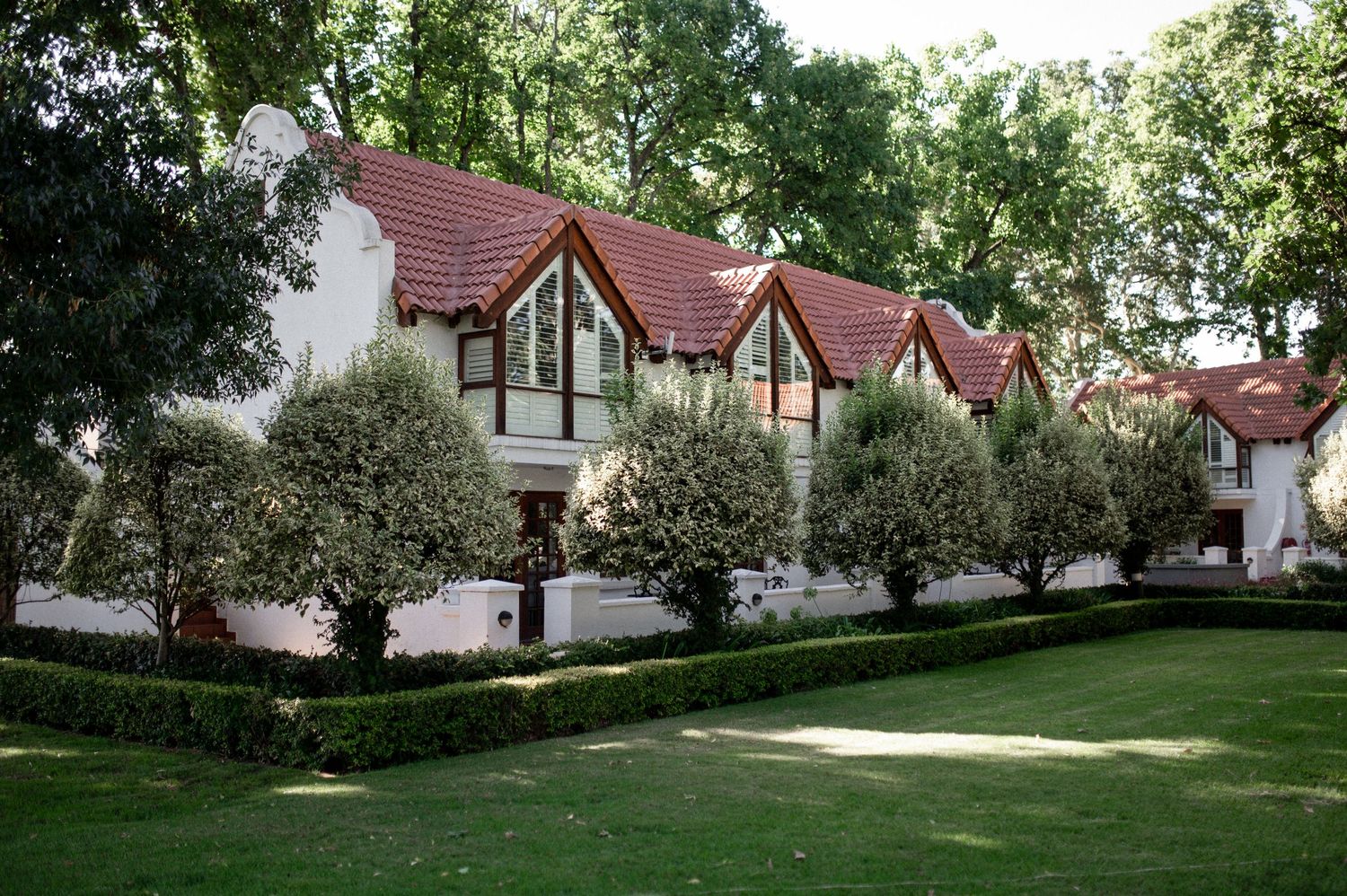 Row of Tudor-style houses with red roofs and manicured gardens.