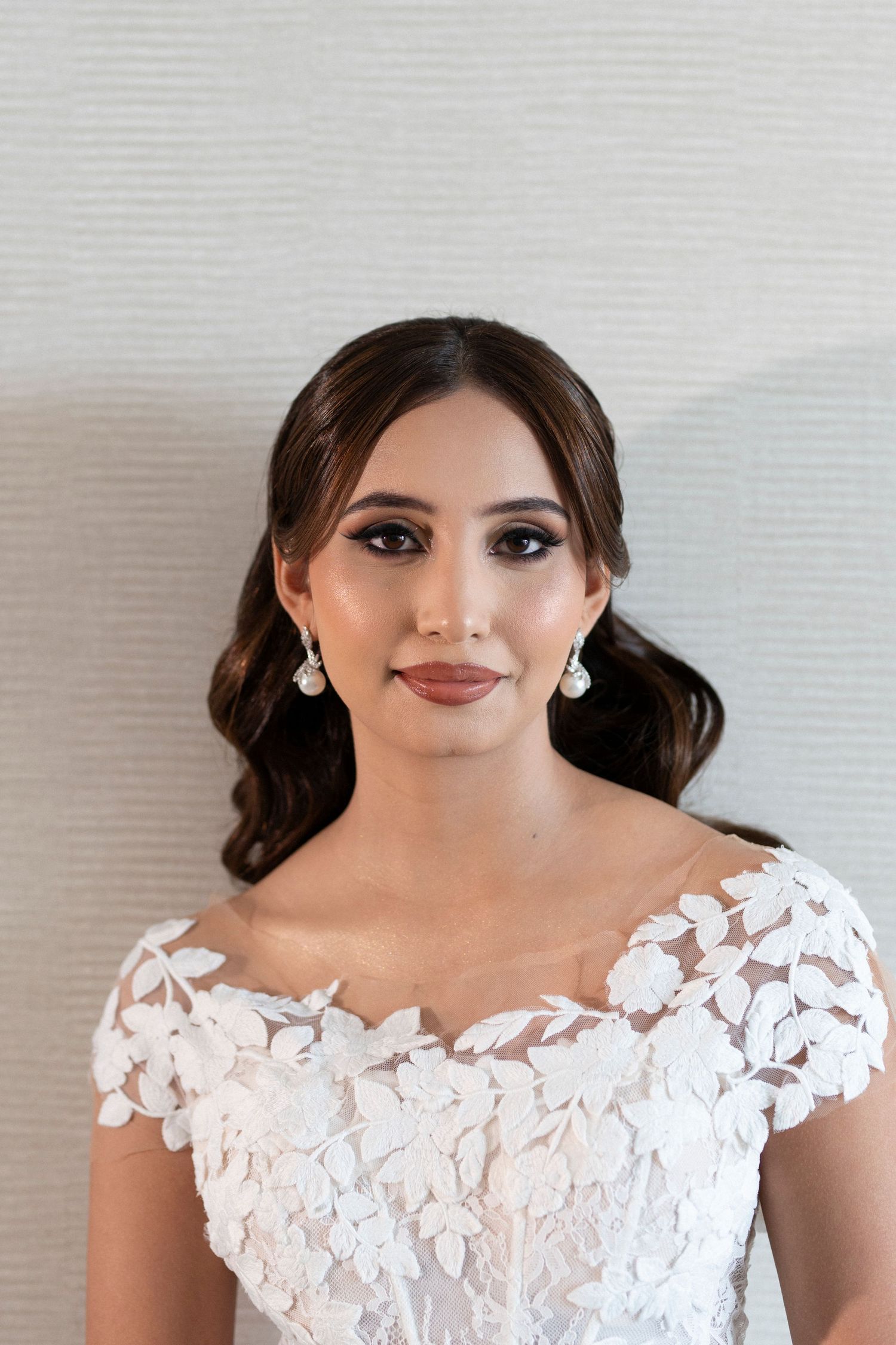 Bridal portrait showing detailed lace wedding dress and elegant jewelry.