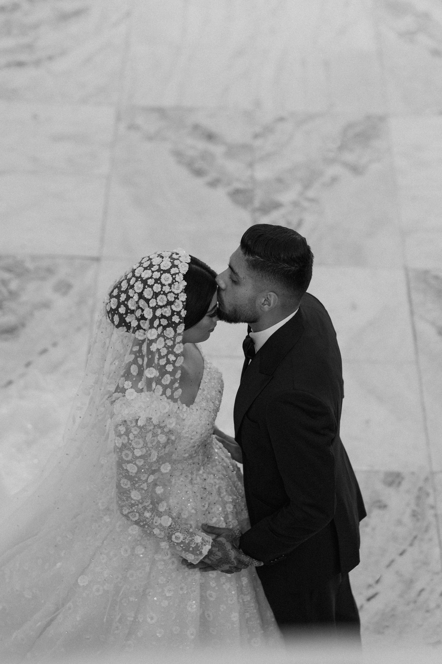 Intimate black and white moment of newlyweds sharing their first kiss.