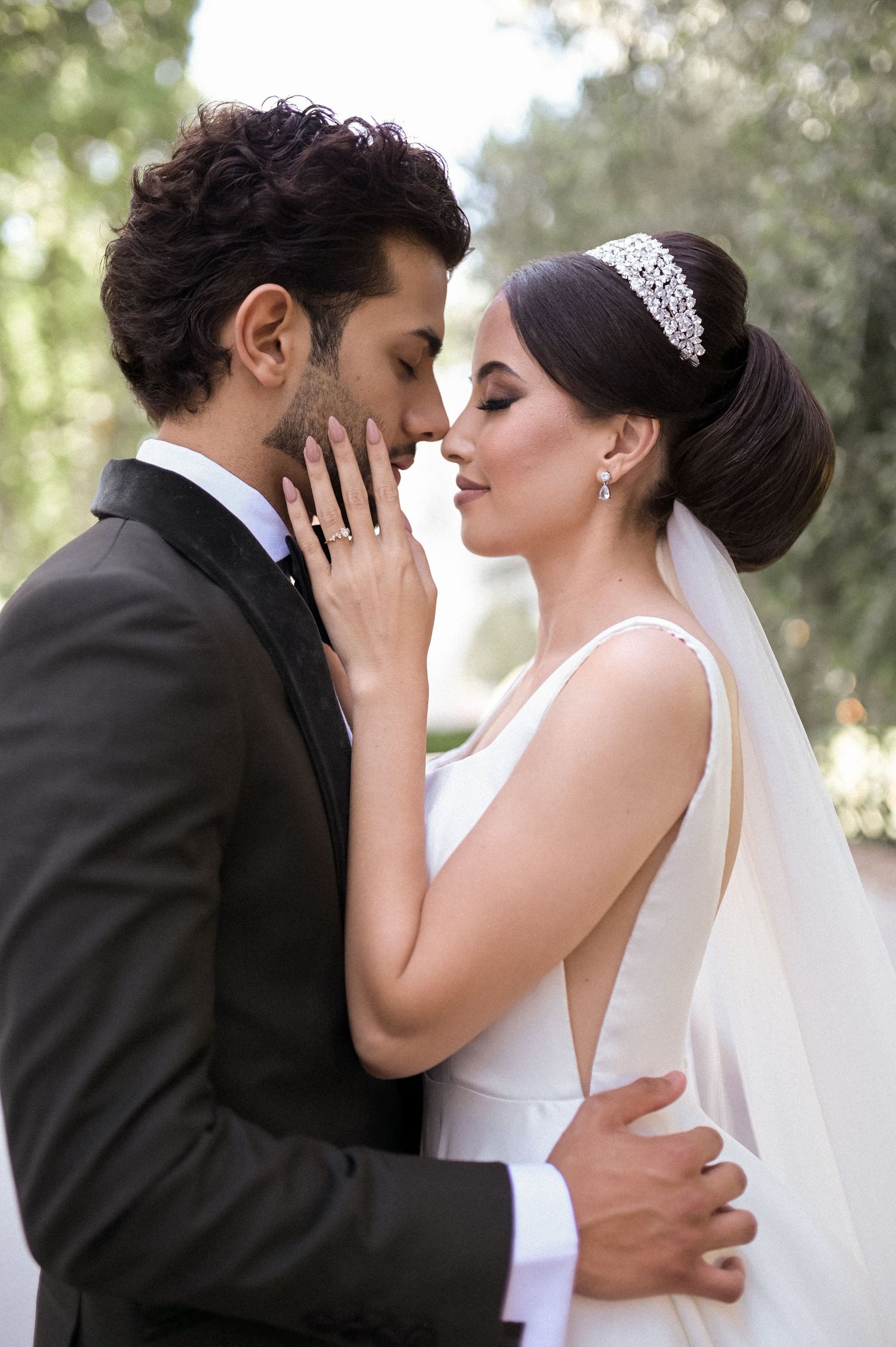 Romantic wedding couple sharing intimate moment outdoors with bride in white gown.