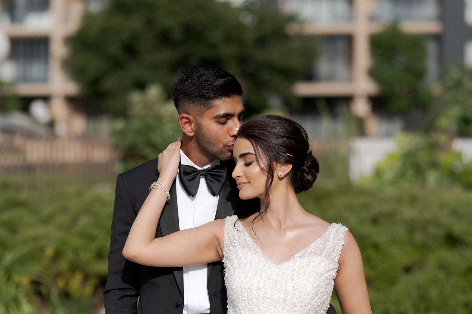 Romantic outdoor portrait of bride and groom in formal wedding attire.