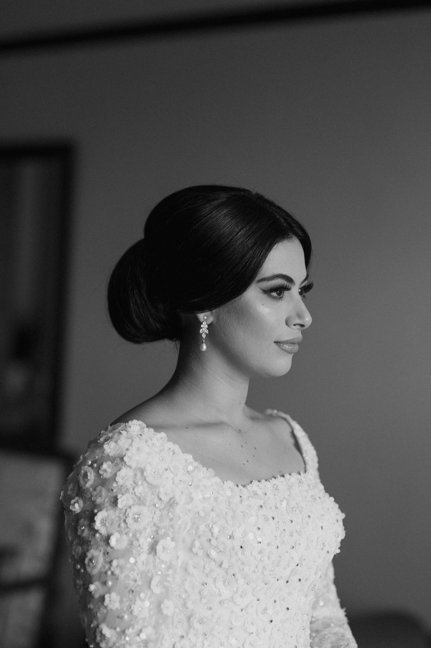 Elegant bride with a sophisticated updo hairstyle wearing a beaded white wedding dress.