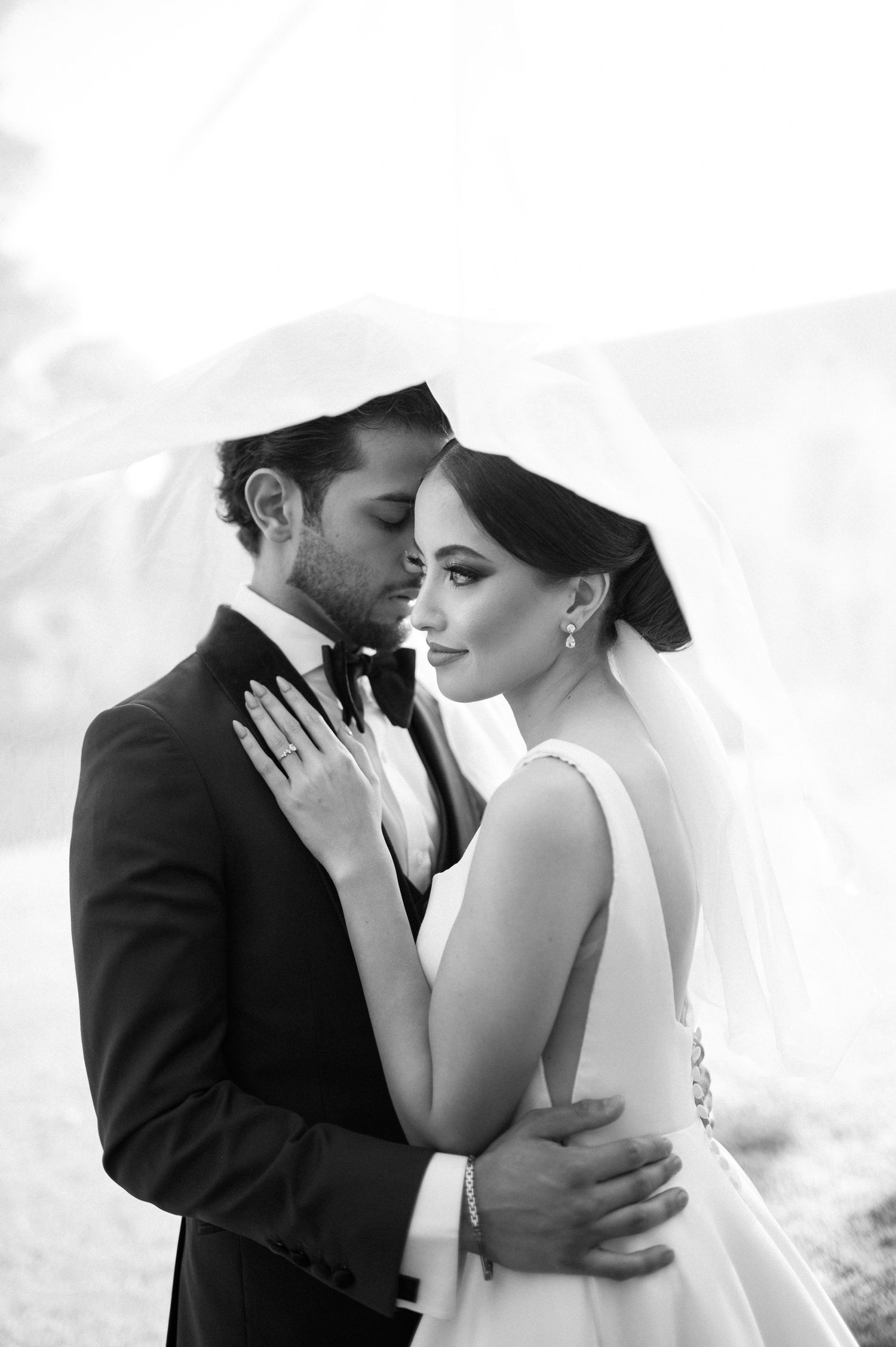 An intimate black and white wedding portrait showing a tender embrace between newlyweds.