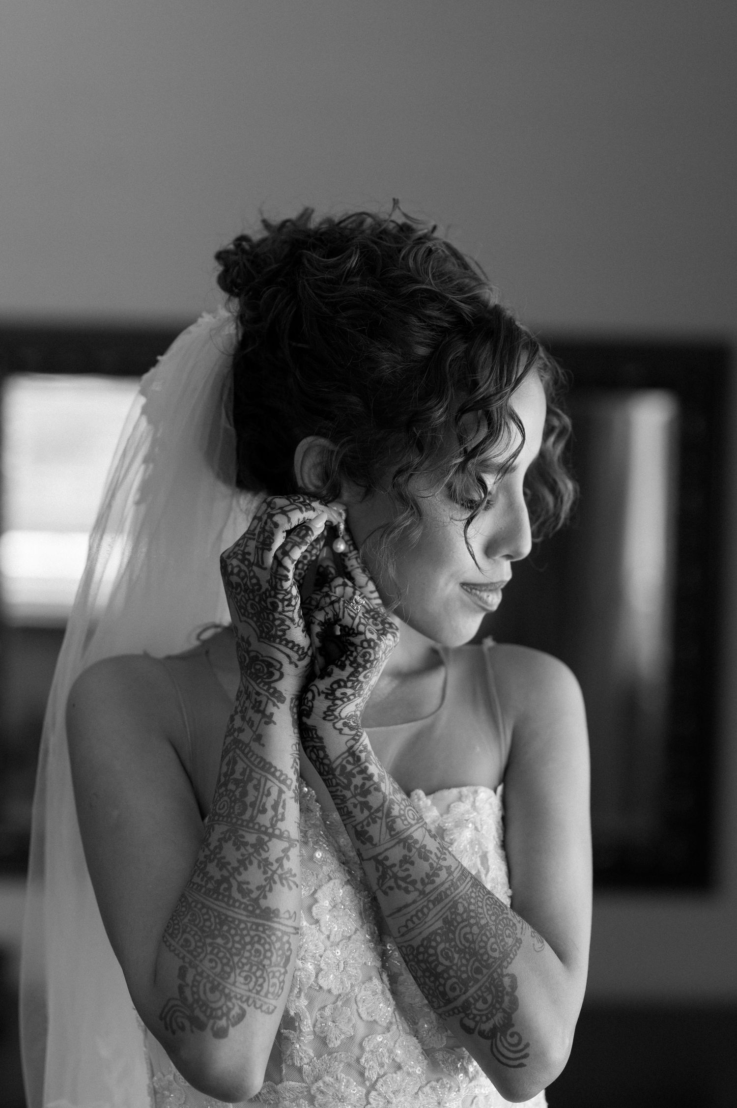 Artistic black and white photo of bride with henna designs and veil.