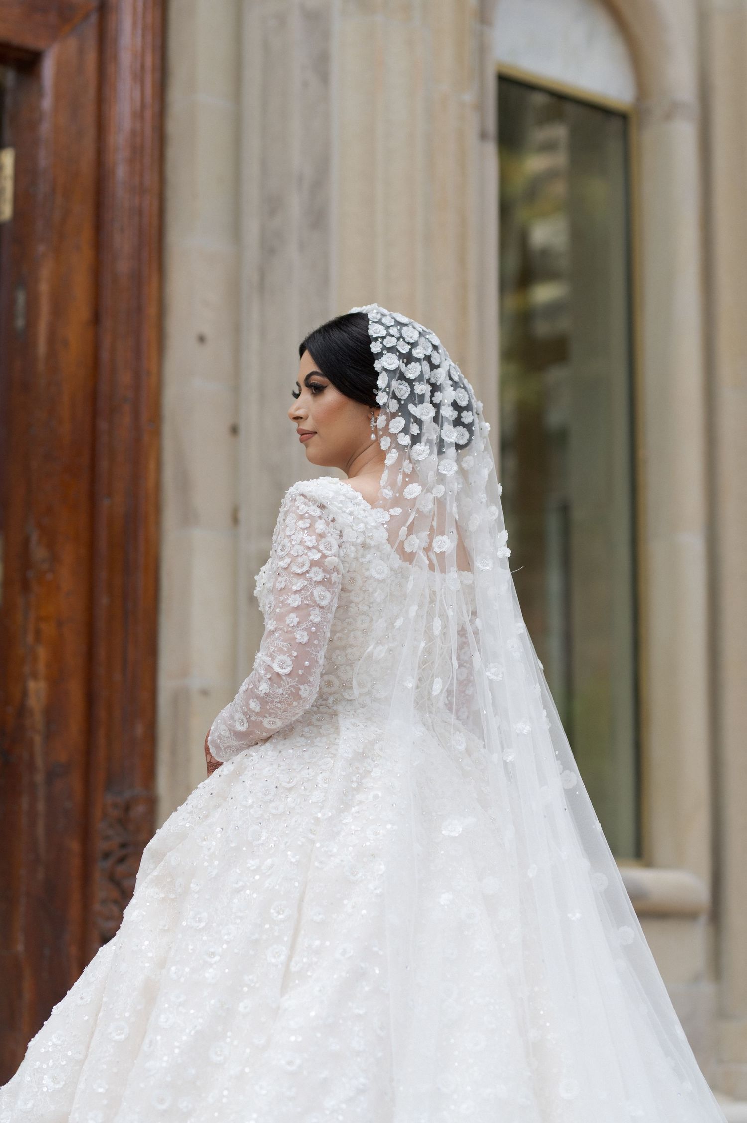 Bride in a luxurious lace wedding dress with intricate veil detailing captured from behind.