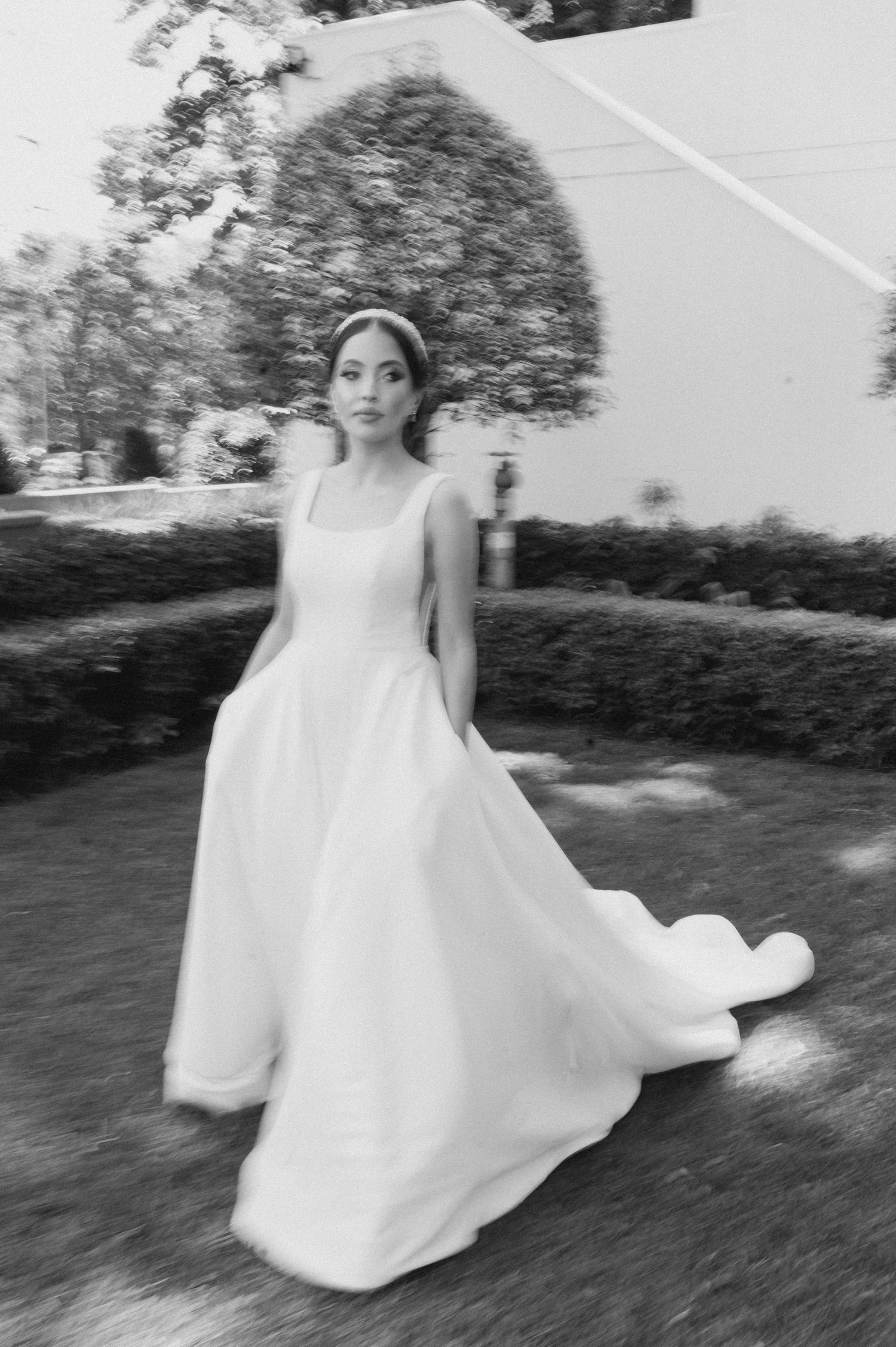 Black and white portrait of bride in flowing gown outdoors.