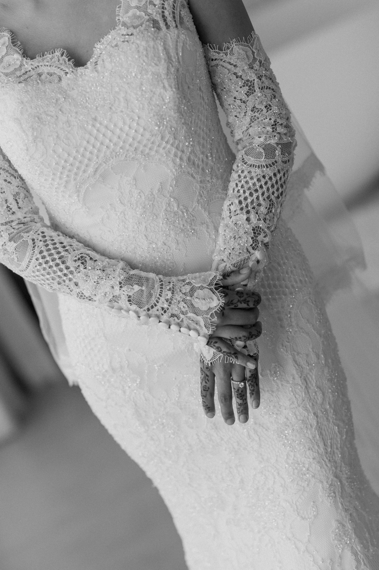 Detail shot of intricate lace wedding dress sleeve and bodice in black and white.