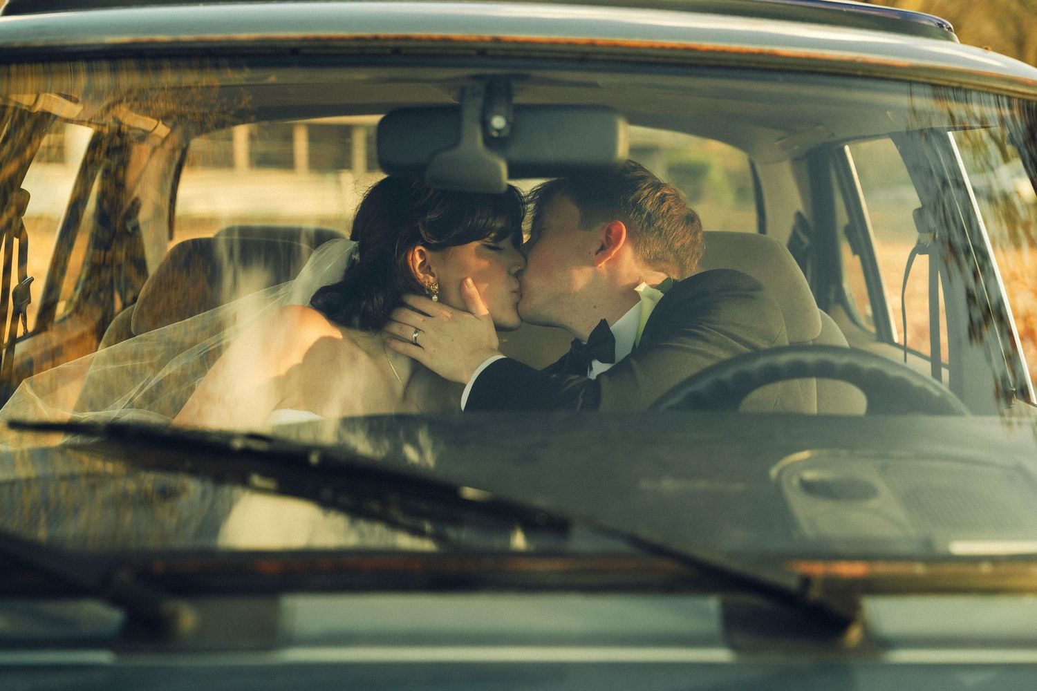 Two people sit in a car with yellow tinted lighting as seen through multiple car windows in a cinematic sequence.