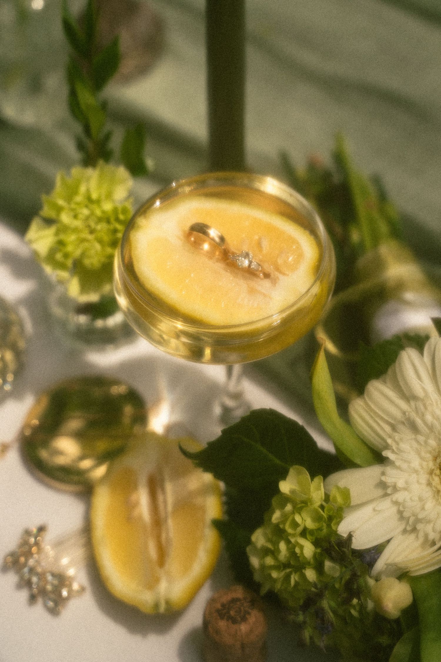 A golden cocktail garnished with flowers and citrus on an elegant white tablecloth.