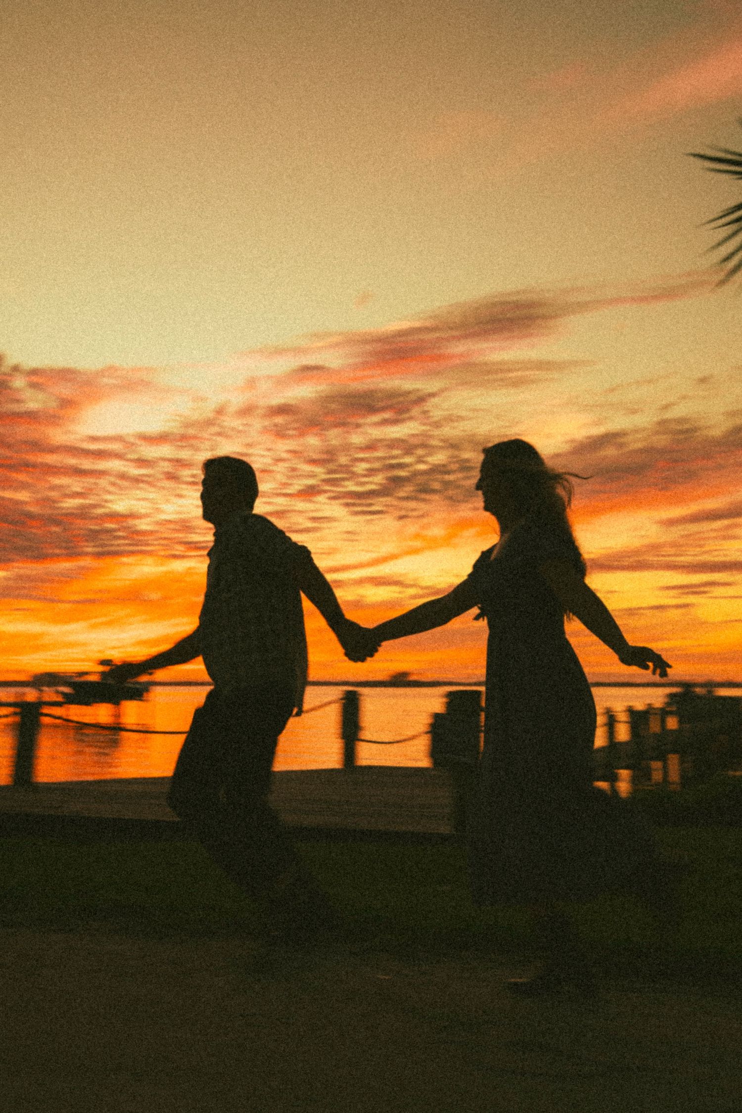 Silhouettes of people playing and dancing against a vibrant sunset sky.