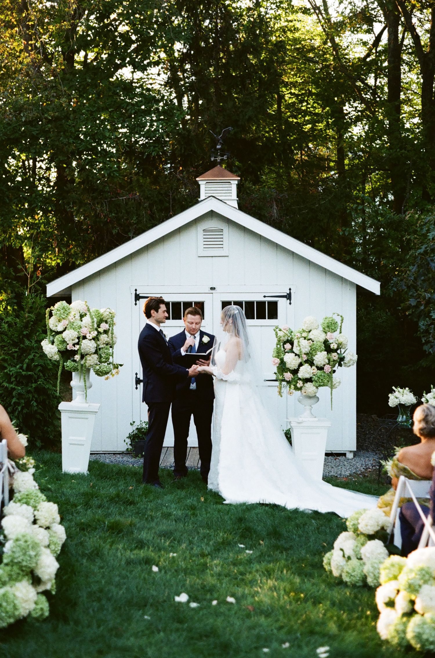 Small white chapel decorated with hydrangea flowers for an outdoor wedding ceremony.