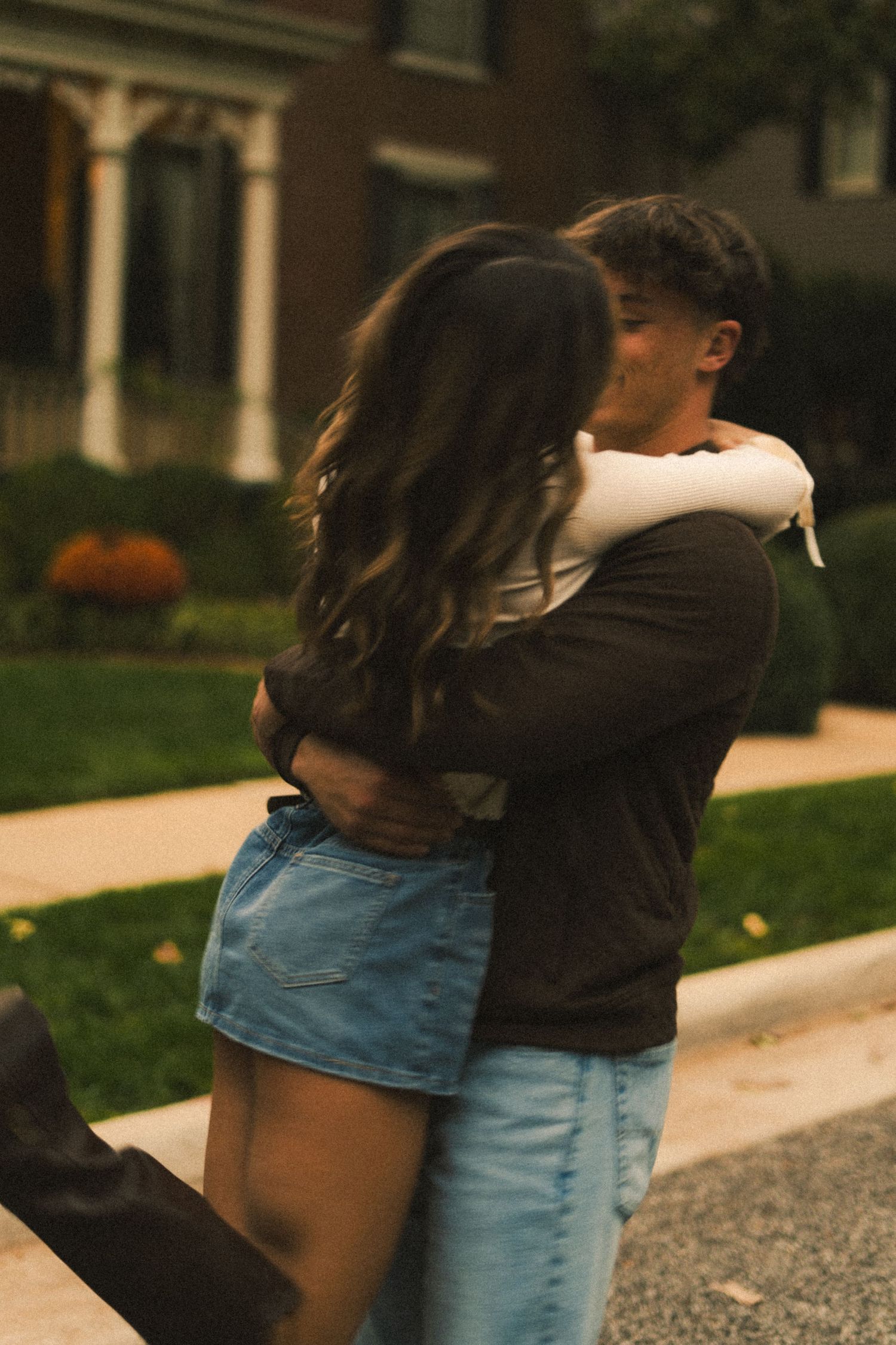 Two people embracing on a path surrounded by fallen leaves.