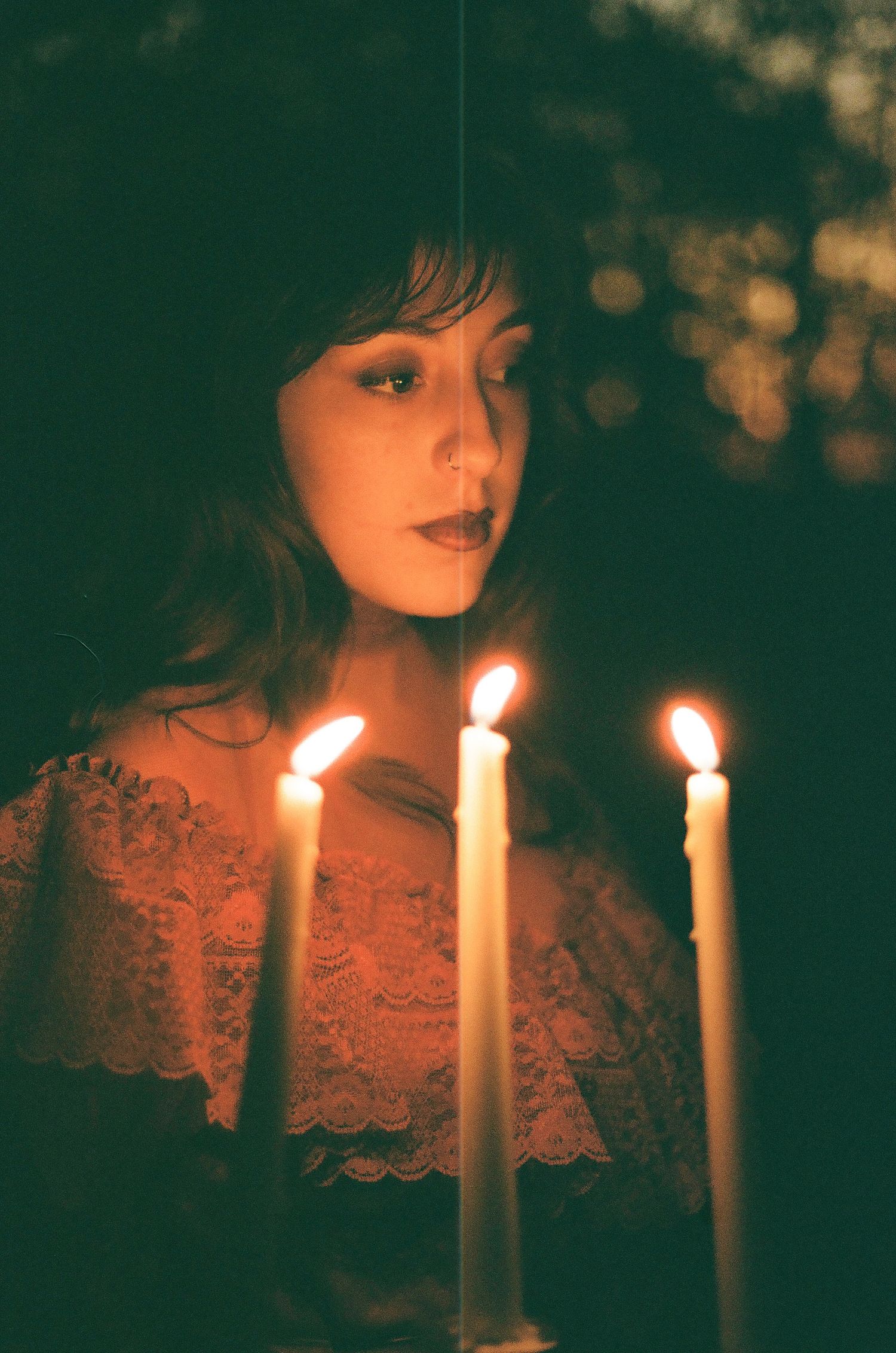 Atmospheric portrait with glowing candles creating warm lighting effects.
