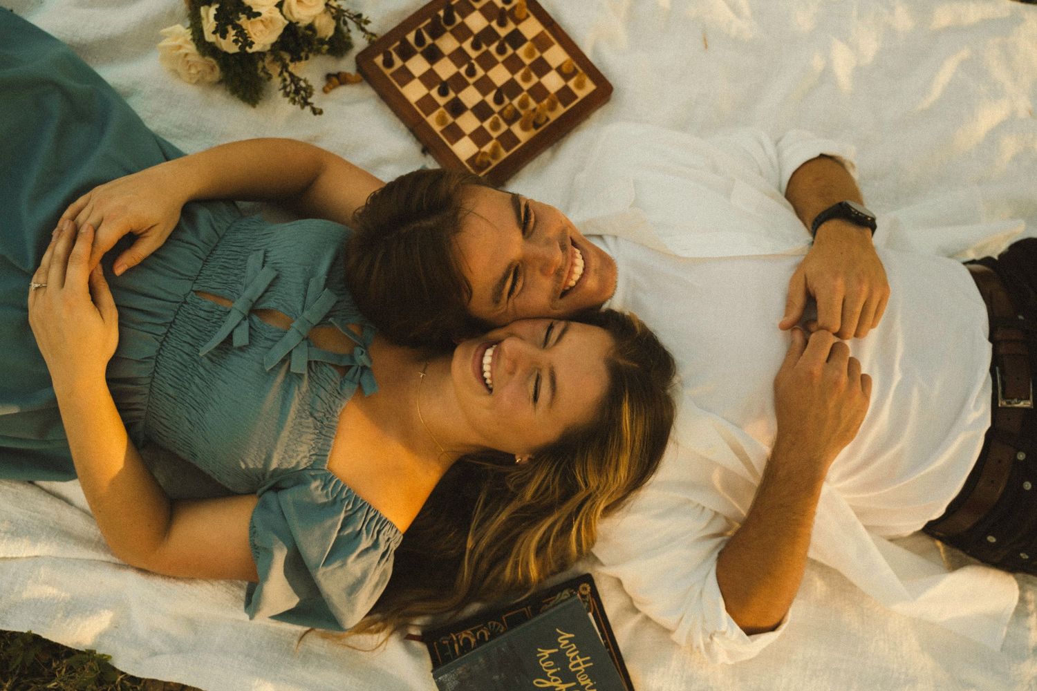 A person lying down on white bedding wearing a teal colored shirt in a sequence of similar poses.