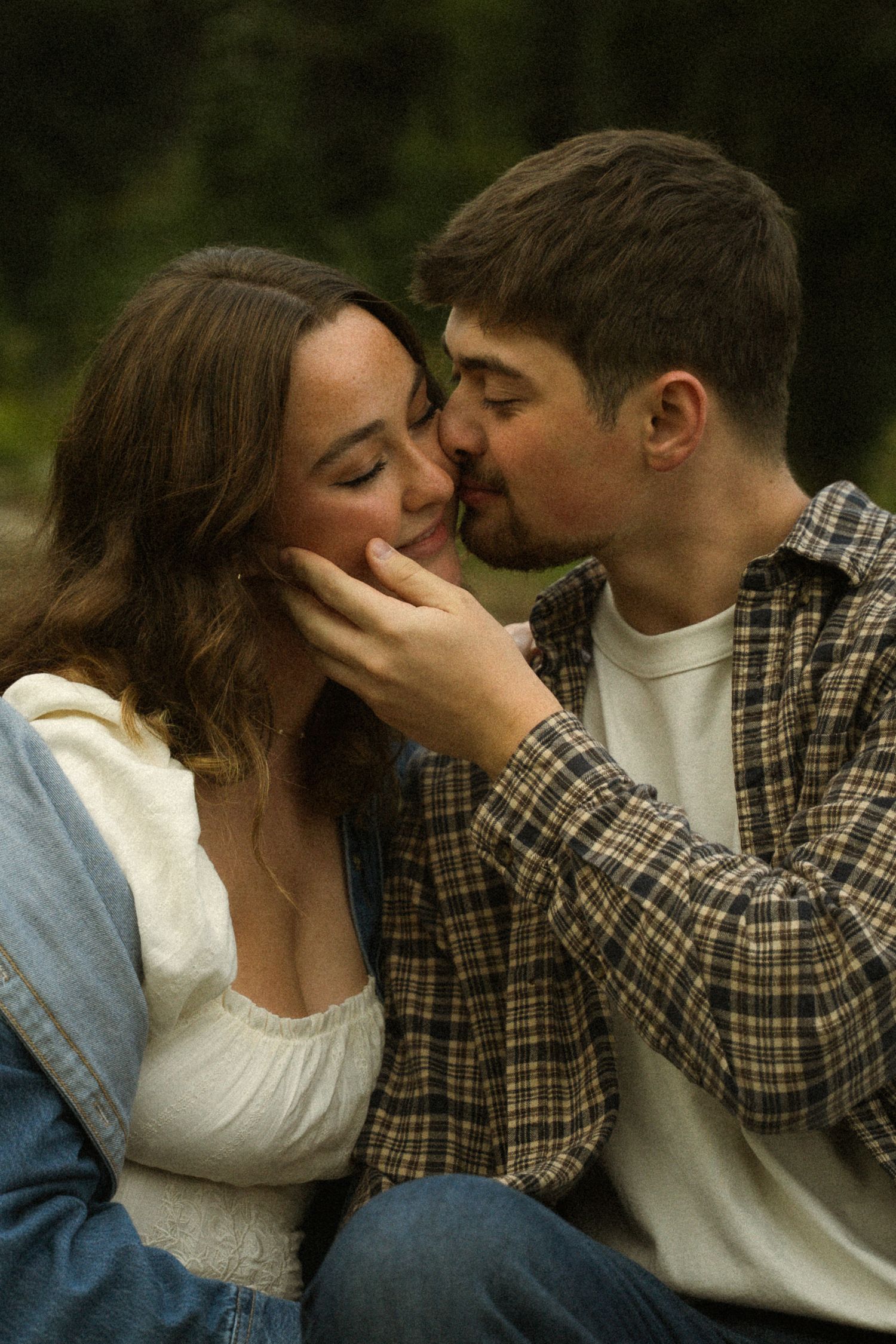 Intimate close-up of couple sharing romantic moment outdoors in casual attire.