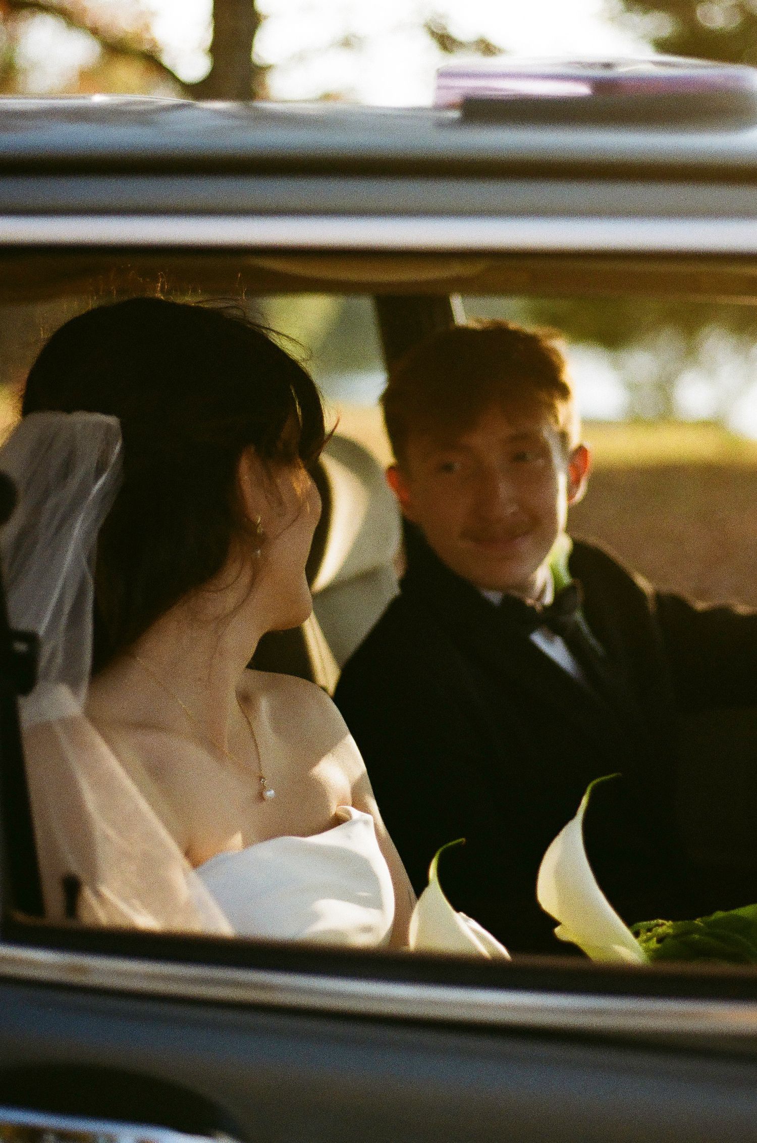 Wedding couple sitting in a car seen through the window.