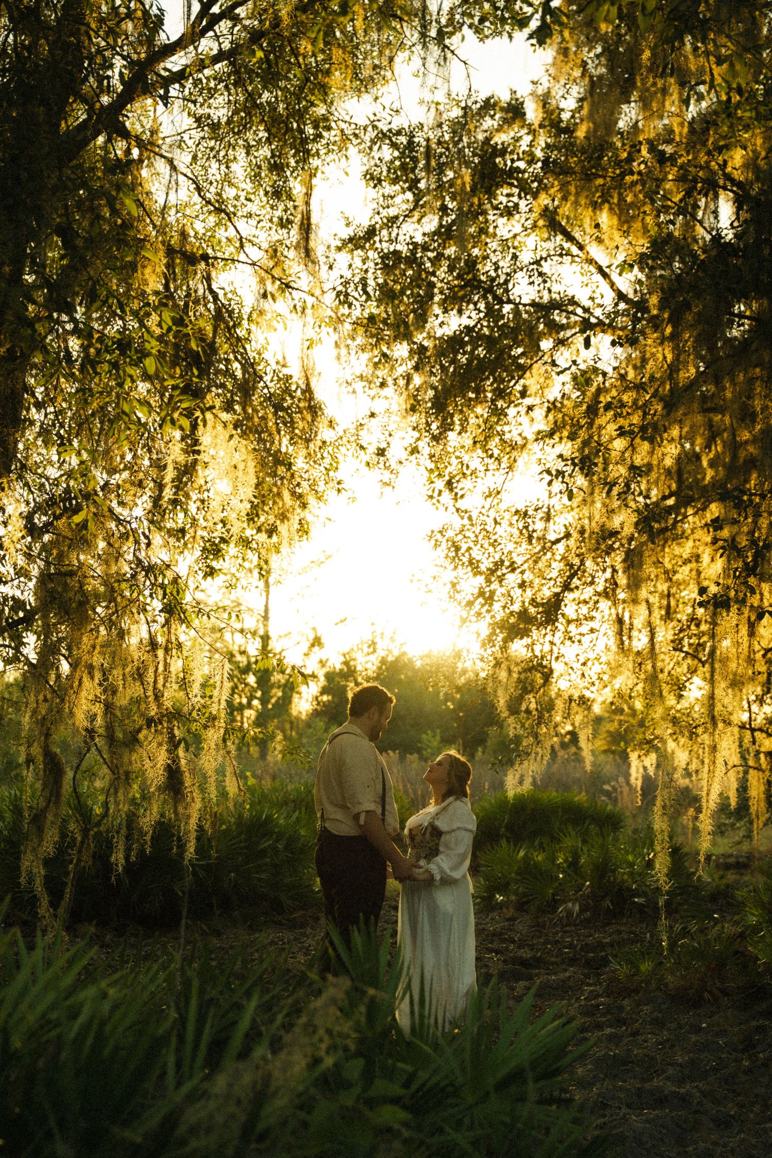 Silhouettes of people standing in a forest during golden hour sunset.